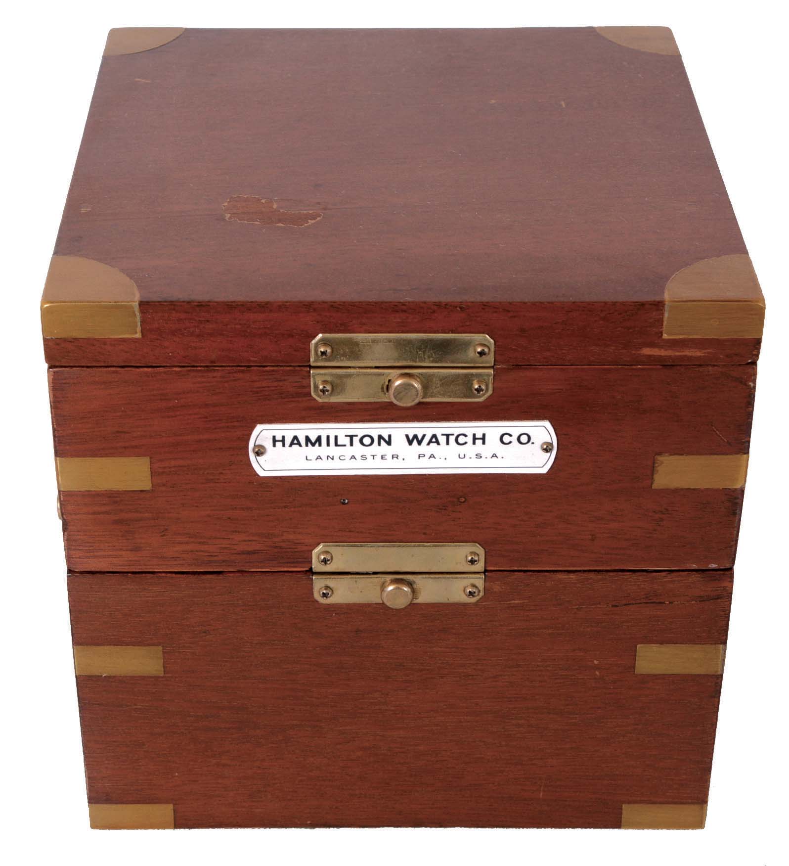 Hamilton Watch Co., Lancaster, Penn., model 21 marine chronometer, 14 jewel key wind and set, straight line damascened nickel plate movement, with spring detent escapement and chronometer balance with helical hairspring, and Arabic numeral metal dial with wind indicator, black painted steel spade and poker hands, contained in a gimbaled mahogany box with brass hardware, the inside of the box top with printed instruction sheet, serial #2E2088, c1940 — Antique Clocks Price Guide