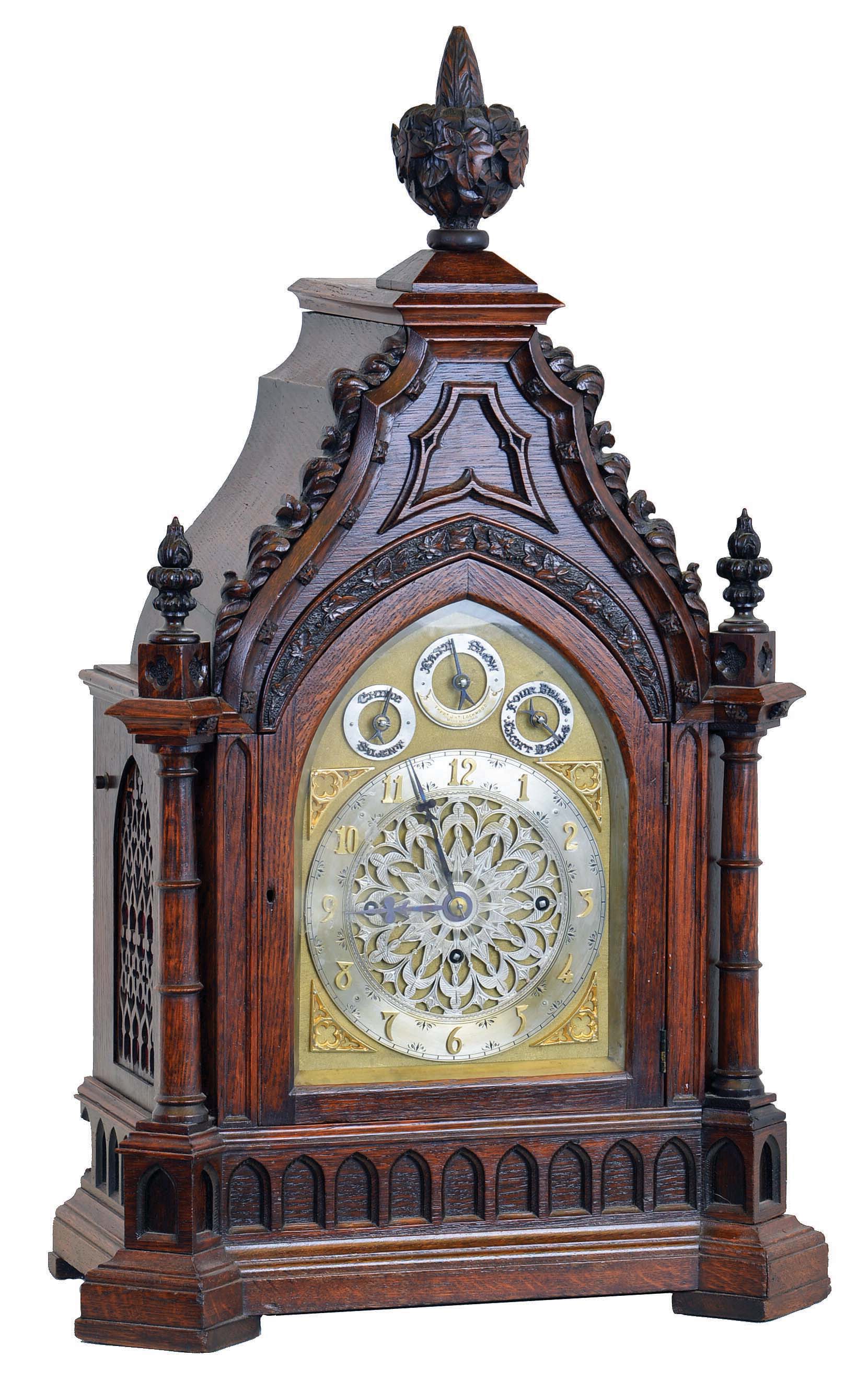 Frederick James Lockwood, West Norwood, London, large bracket clock in the Gothic style, carved oak case with buttress corners supporting turned columns, the molded base with lancet arch blind fret, lancet arch door below a carved lintel, the tympanum with applied, modified foil and hawksbill molding, all topped with foliate carving and decorative finials, case sides with pierced wooden frets, Arabic numeral silvered dial with gilt spandrels, with subsidiary dials for selecting chime tune, mode and regulation, blued steel hands, and substantial, 8 day, 3 train fusee movement, sounding the quarters on four or eight bells and counting the hours on a large gong, the back plate also signed , c1845 — Antique Clocks Price Guide