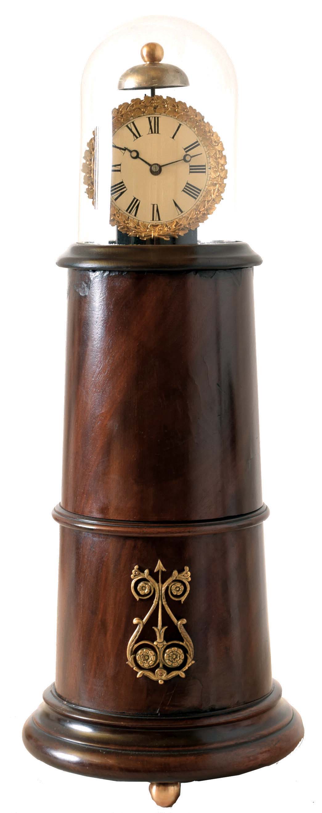 Light house clock case in the manner of Simon Willard, turned mahogany and mahogany veneer on brass ball feet, the front with applied gilt ornament, white painted Roman numeral dial with gilt bezel, mounted to a wooden block, with glass dome, 20th century — Antique Clocks Price Guide