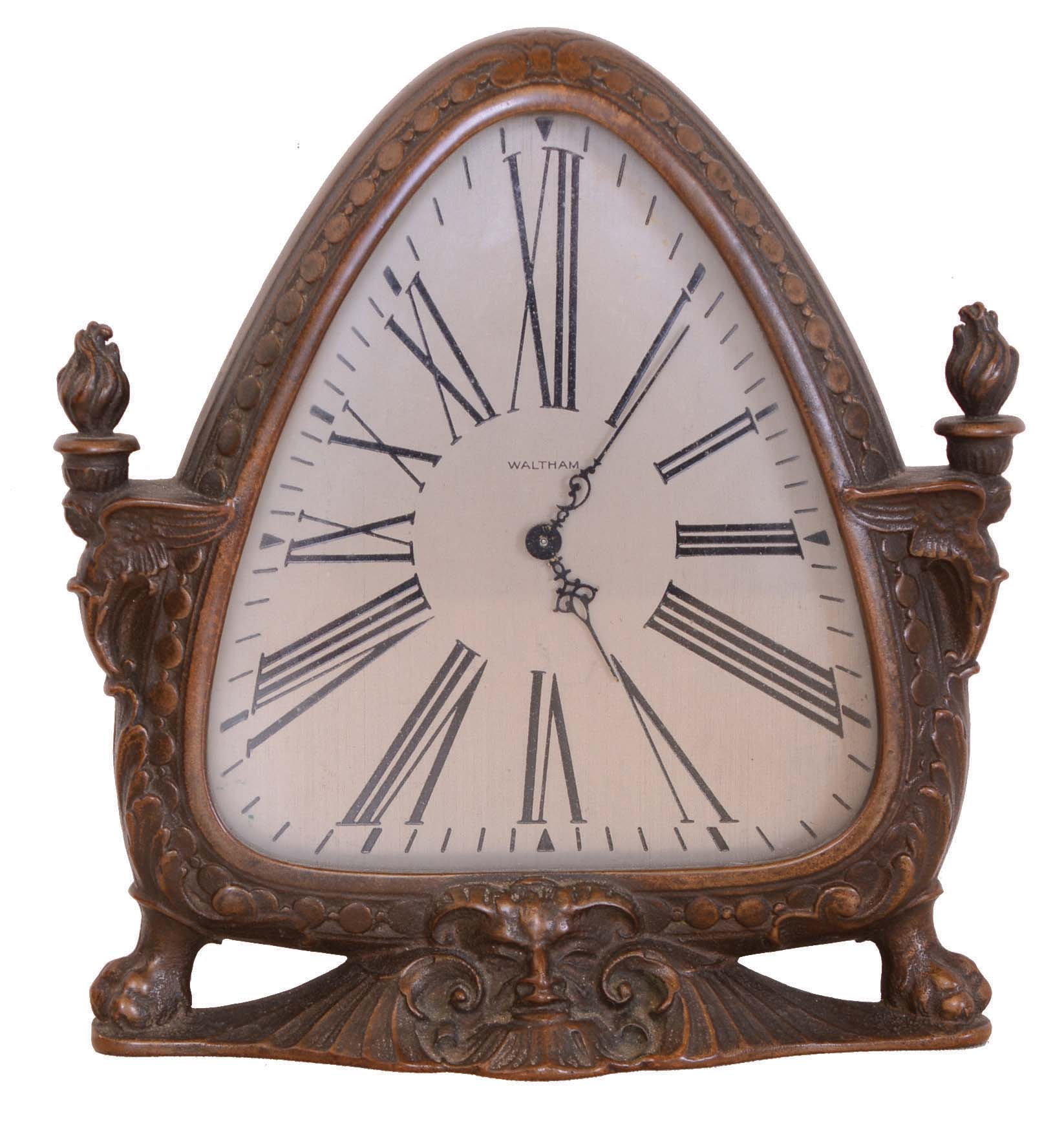 Waltham Clock Co., Waltham, Mass., cast bronze timepiece, the patinated case with satyr mask at center of base, sides with caryatids bearing torches on their heads, and with paw feet, Roman numeral, silvered triangular dial, 8 day time only movement — Antique Clocks Price Guide