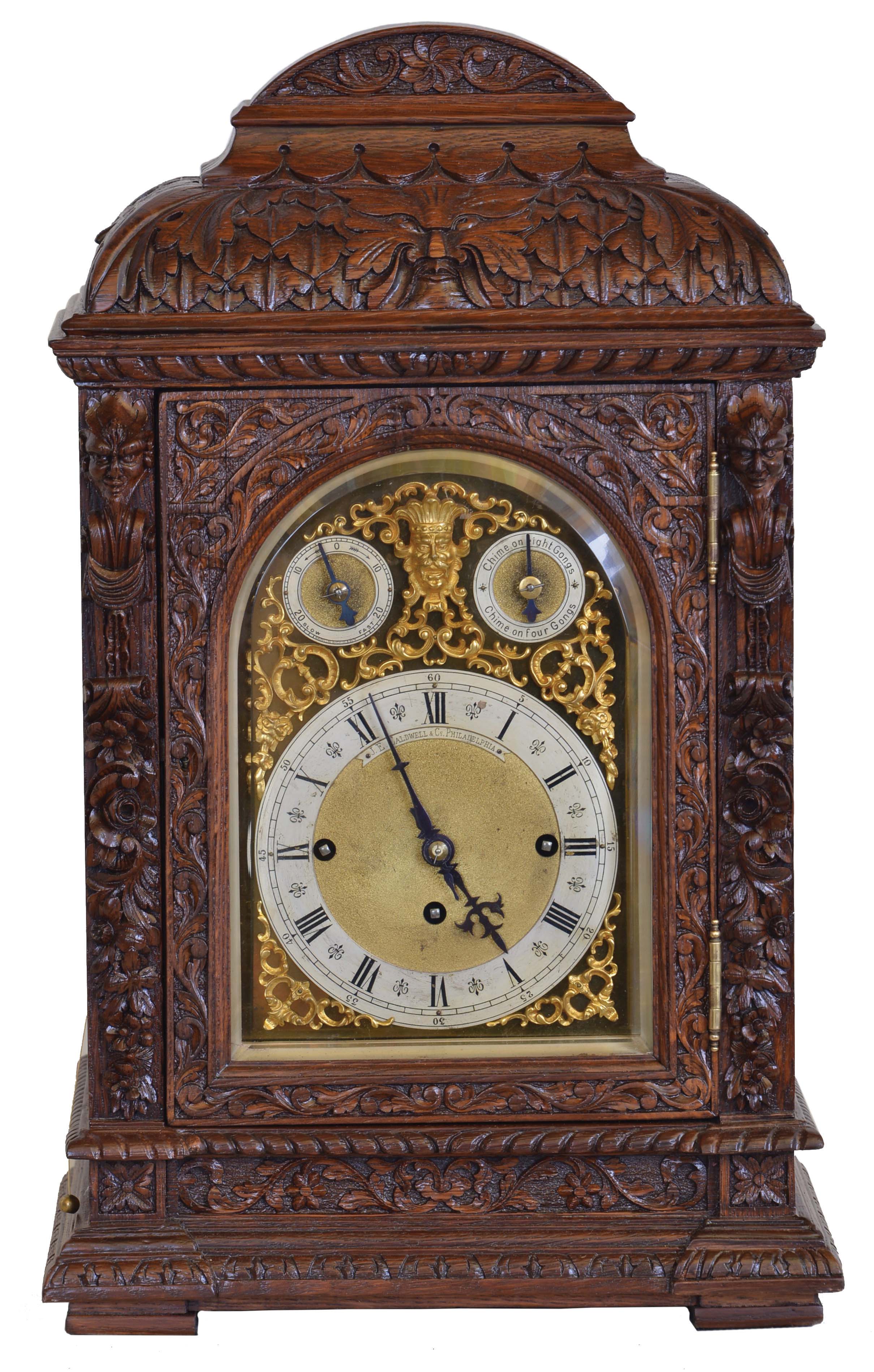 Winterhalder & Hofmeier, Germany, for J.E Caldwell & Co., Philadelphia, a large three train bracket clock, the oak case richly ornamented with low and high relief carving, door with beveled glass, composite dial with Roman numeral chapter ring, matted center, gilt baroque spandrels, and with rating and chime selection dials in the arch, blued steel hands, 8 day, three train fusee movement chiming on four or eight gongs at the quarters, the fourth quarter also with hour striking, and with grand sonnerie repeating on demand — Antique Clocks Price Guide