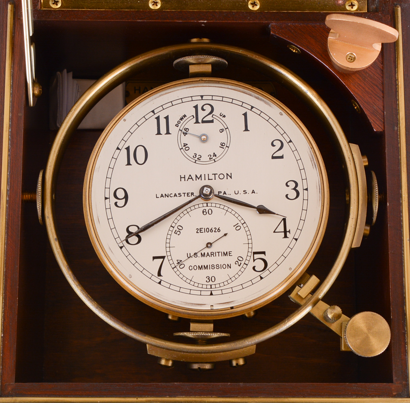 Hamilton Watch Co., Lancaster, Penn., model 21 marine Chronometer, 14 jewel key wind and set, straight line damascened nickel plate movement, with spring detent escapement and Chronometer balance with helical hairspring, Arabic numeral metal dial with wind indicator, engraved "U.S. Maritime Commission", black painted steel spade and poker hands, contained in a gimbaled mahogany box with brass hardware, the front with U.S. Maritime commission plaque, and the inside of the box top with instruction plate, serial #2E10626, c1945 — Antique Clocks Price Guide