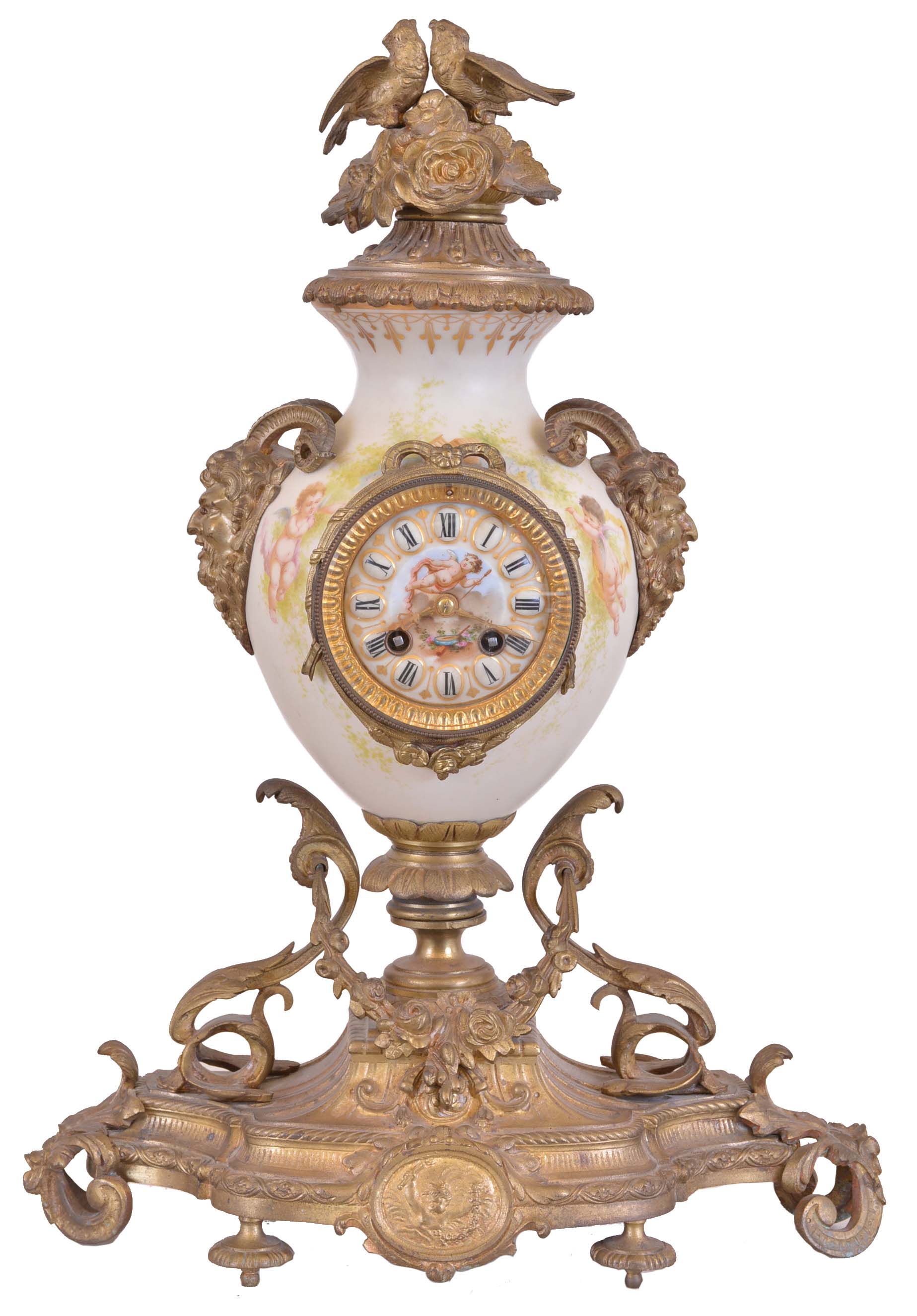 France, mantel clock, the vase form porcelain case with painted putti flanking the dial, satyr mask handles, the top with flowers and a pair of birds, all on a gilt base with foliate ornament, porcelain dial with Roman numerals, gilding, and central polychrome putto, gilt hands, and 8 day time and strike pendule de Paris movement — Antique Clocks Price Guide