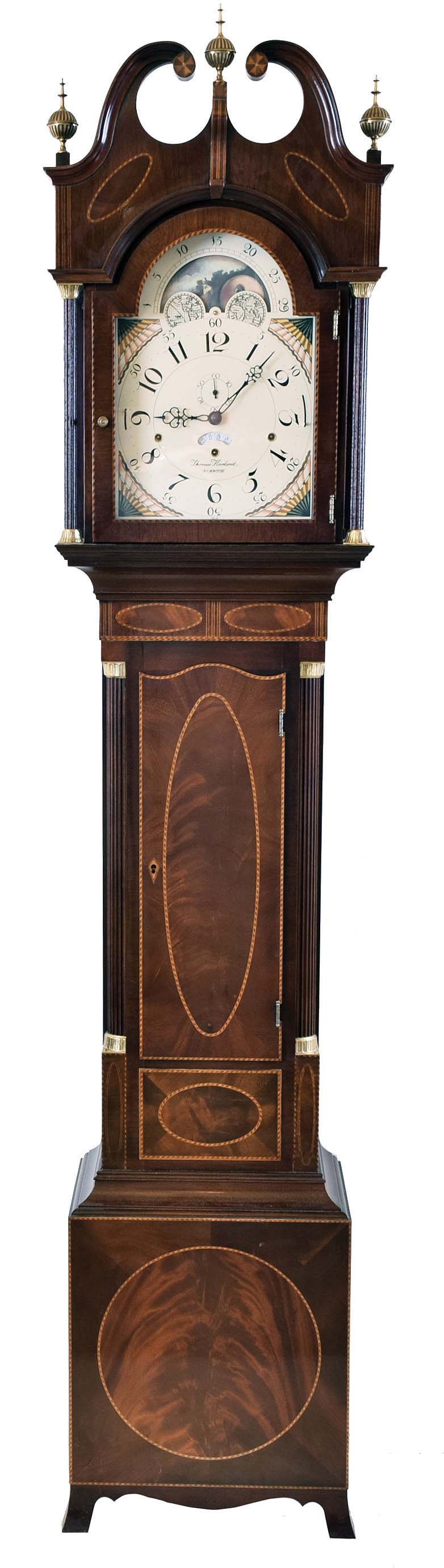 The Henry Ford Museum, Dearborn, Michigan reproduction by Sligh signed Thomas Harland, Norwich Conn., tall case clock, 8 day, time, strike and triple chime, weight driven movement in a mahogany Hepplewhite style case with three brass finials, full columns on hood, banded and oval inlays, fluted corner columns on trunk with brass terminals, French feet and moon phase dial — Antique Clocks Price Guide