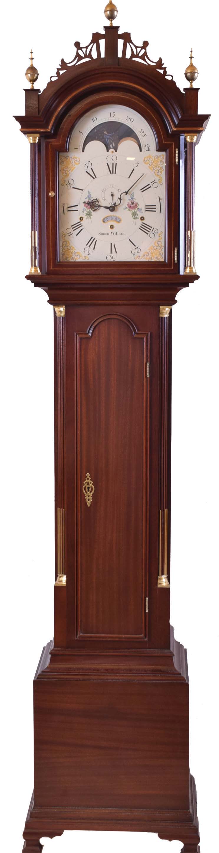 The Henry Ford Museum, Dearborn, Michigan reproduction Simon Willard, Boston, Mass., tall case clock, 8 day, time, strike and triple chime, weight driven movement in a mahogany Roxbury style case with three brass finials, fretwork top, fluted full columns on hood with brass terminals, string inlay, fluted corner columns on trunk with brass terminals, ogee feet and moon phase dial — Antique Clocks Price Guide