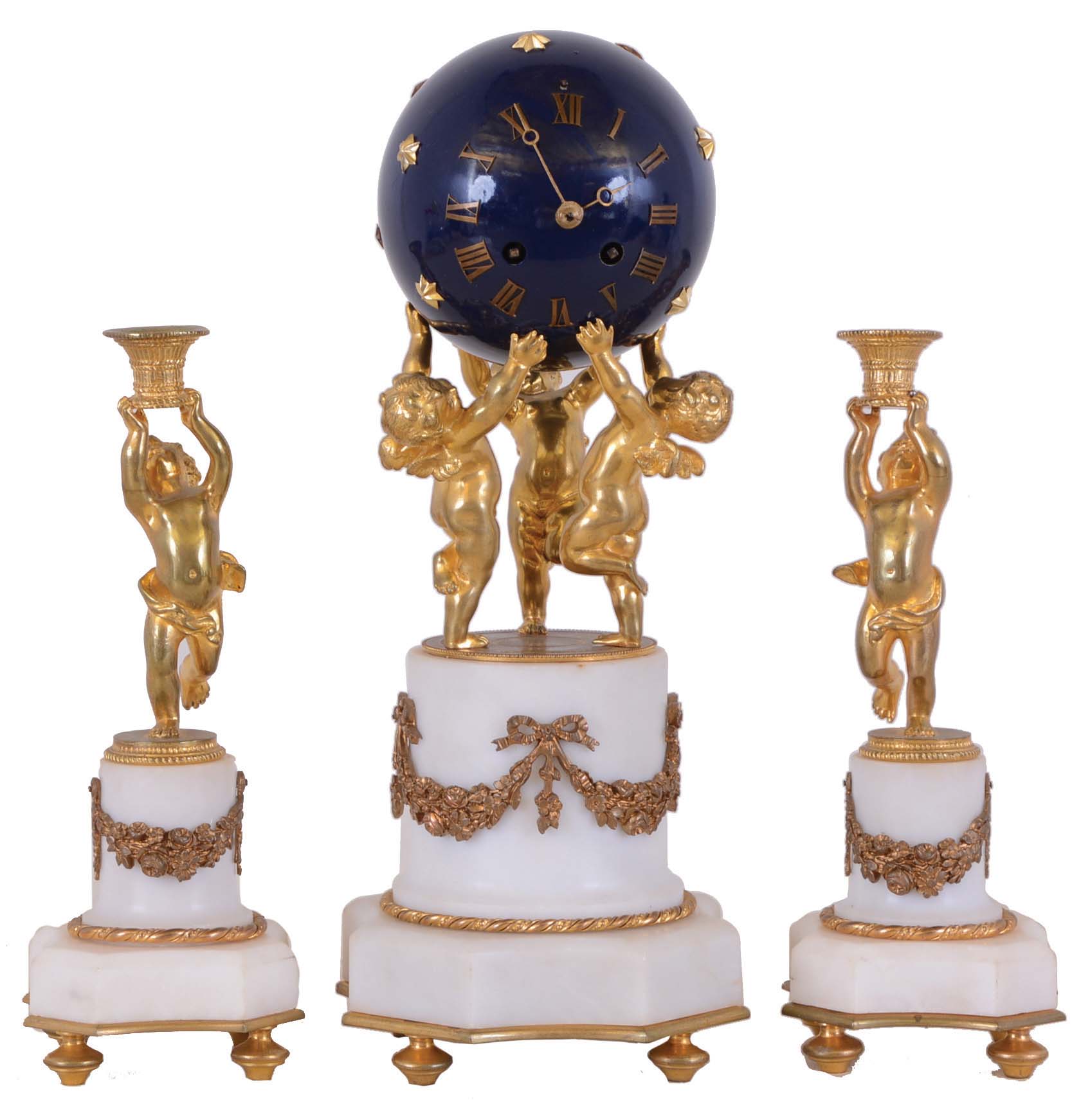 France, mantel clock with garniture, the white marble base with incurved corners, supporting an attenuated column ornamented with gilt floral swags, all surmounted by three dancing putti, holding aloft a blue, painted sphere with gilt Roman numerals and stars, containing an 8 day, time and strike, pendule de Paris movement, the matching garniture also with putti, supporting basket form candle holders — Antique Clocks Price Guide