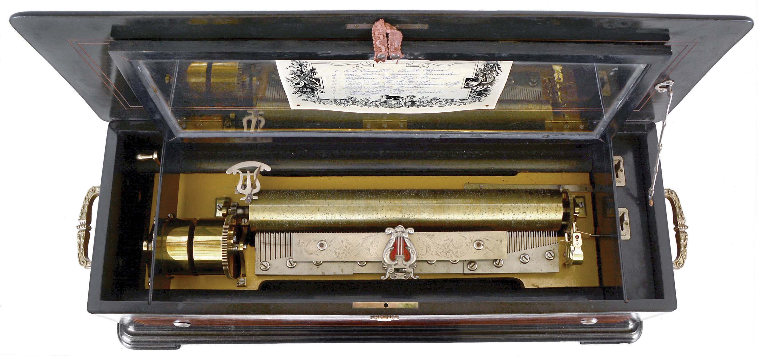 Paillard, Geneva, cylinder music box, ebonized case with burl walnut panels and contrasting, banded borders, turned and carved escutcheon, the ends with ornate brass carrying handles, and the top with central boulle style ornament, the glazed frame protecting the movement with gilt, molded edge, and repeating gilt foliate pattern, 17 inch cylinder playing eight tunes, three section comb, and driven by two large springs with Geneva stopwork — Antique Clocks Price Guide