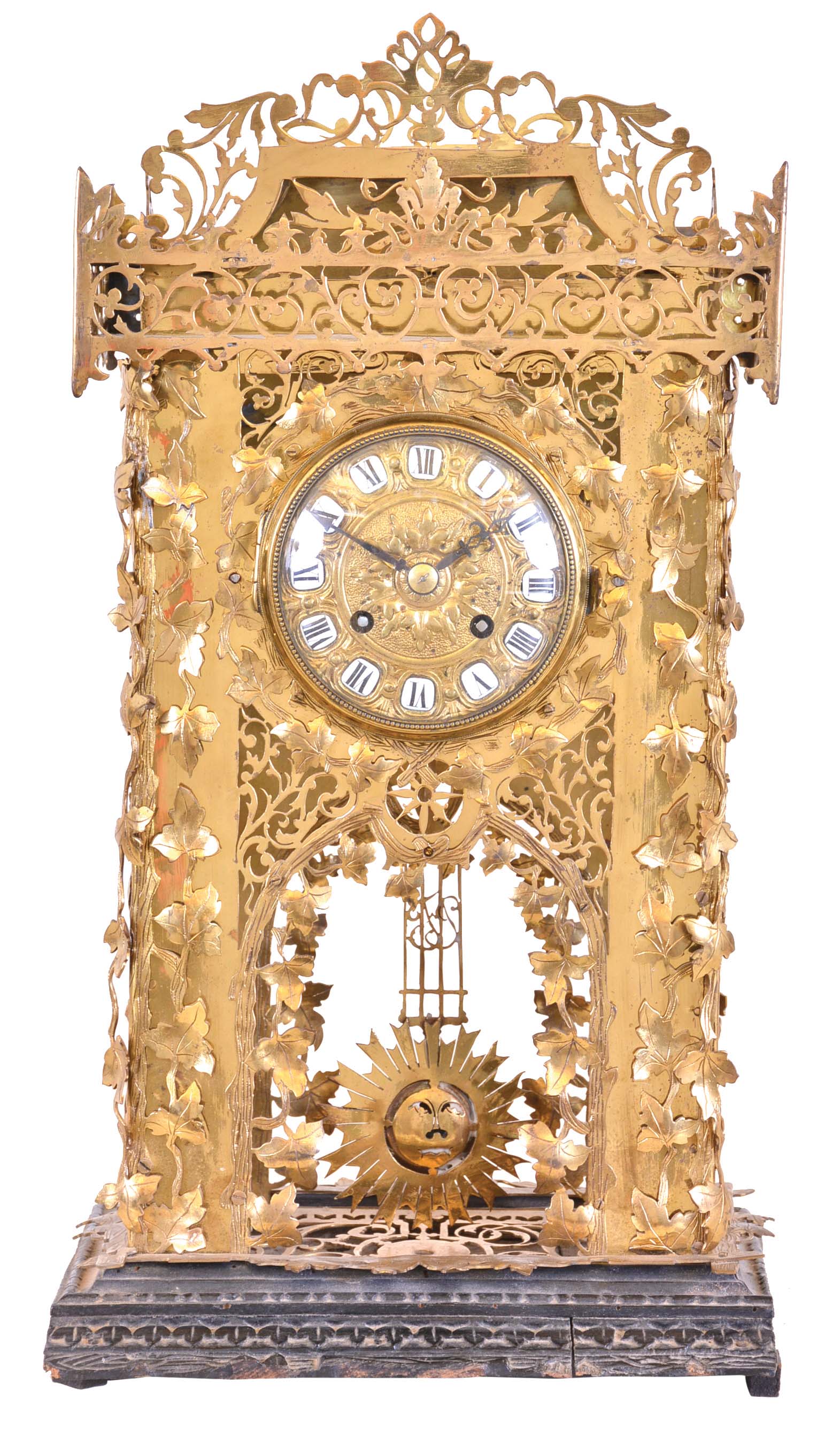 Mantel or table clock, the brass case with elaborate piercing, and applied brass leaves and vines, mounted to a similarly carved wooden base, the overall design seemingly inspired by the carving on Black Forest cuckoo clocks, cast dial with repousse style ornament, and white enamel, Roman numeral cartouches, blued steel hands, and 8 day time and strike pendule de Paris movement, signed Dumoulinneuf Paris — Antique Clocks Price Guide