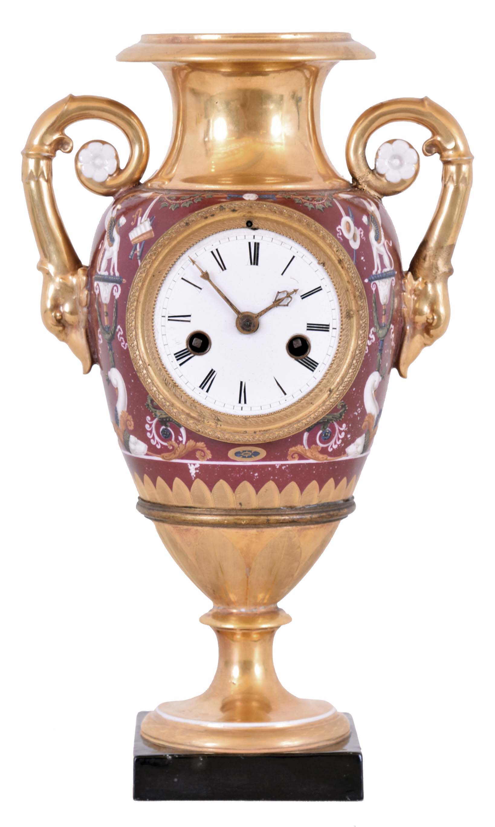 France, Paris porcelain table or mantel clock with urn form case, the base decorated with bright and matte gilt leaves, the body with maroon ground, and polychrome neoclassical and Grecian ornament, gilt swan handles, Roman numeral white enamel dial with engine turned bezel and original gilt, cast hands, 8 day time and strike pendule de Paris movement with silk thread suspension — Antique Clocks Price Guide