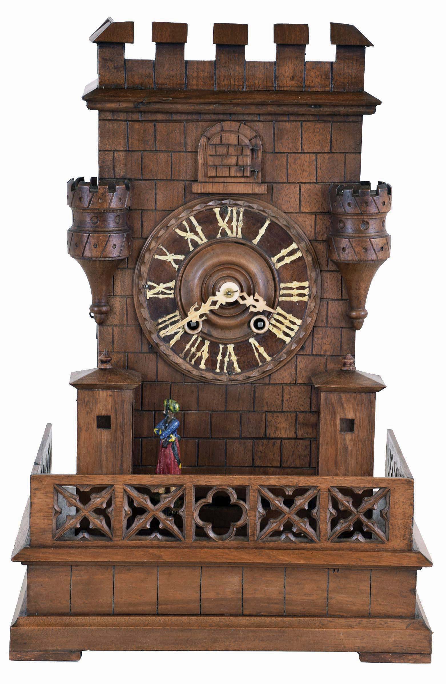 Germany, shelf cuckoo with sentry automata, carved wooden architectural case of Gothic design, molded base with pierced railing enclosing the structure; the building with guard shelters, turrets, and crenellated parapet, and Turkish guard marching back and forth between the shelters as the clock runs, Roman numeral wooden dial, pierced bone hands, 30 hour brass time and strike movement, with carved, painted cuckoo — Antique Clocks Price Guide