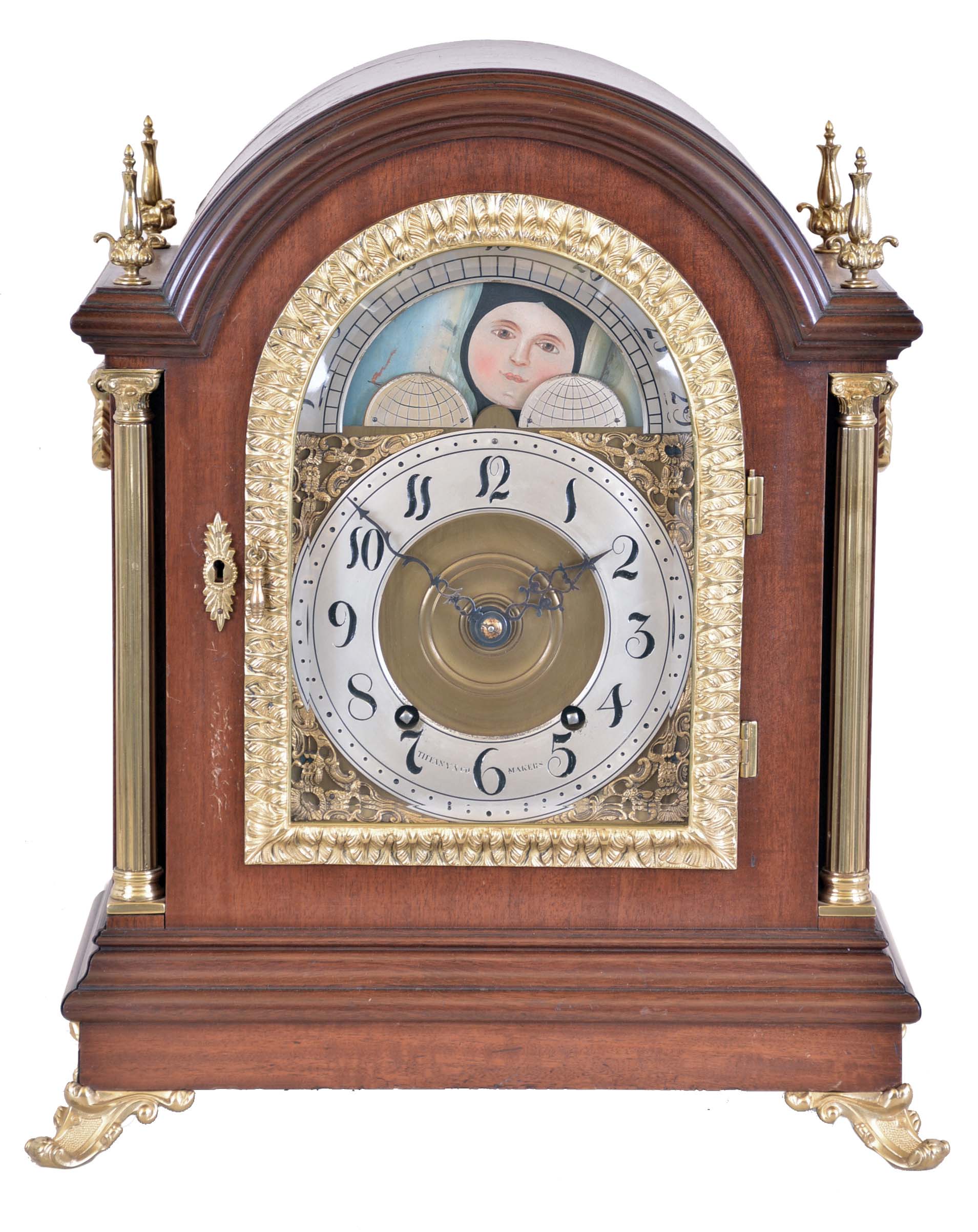 Tiffany & Co. Makers, New York, large mahogany bracket clock, mahogany case with cast brass scroll feet, brass Corinthian columns flanking the arched, cast brass door with acanthus leaf decoration and thick beveled glass, each side with fabric lined brass fret and heavy cast carrying handles, the four corners of the top with brass finials, case back with mahogany door and brass screen, composite dial with gilt spandrels and moonphase diaplay in the arch, Arabic numeral silvered chapter ring marked "Tiffany & Co. Makers", pierced, blued steel hands, substantial brass movement with Brocot escapement, back plate marked "Tiffany & Co. Makers " and with the number 692, original pendulum, c1890 — Antique Clocks Price Guide