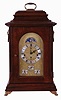 Unknown American mfg bracket clock, with Franz Hermle Westminster chime and calendar movement, and with rolling moon in the arch of the embossed dial. Case with mahogany finish, and with cast feet, handle and side lions. Day of week, date and month in English show on bottom dials.