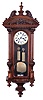Gustav Becker, Germany, hanging regulator, walnut case with carved and turned ornament, Roman numeral two piece enamel dial signed "Rudholzer Klagenfurt", blued steel hands, weight driven time and strike movement, brass pendulum with wooden rod, and brass weights