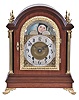 Tiffany & Co. Makers, New York, large mahogany bracket clock, mahogany case with cast brass scroll feet, brass Corinthian columns flanking the arched, cast brass door with acanthus leaf decoration and thick beveled glass, each side with fabric lined brass fret and heavy cast carrying handles, the four corners of the top with brass finials, case back with mahogany door and brass screen, composite dial with gilt spandrels and moonphase diaplay in the arch, Arabic numeral silvered chapter ring marked "Tiffany & Co. Makers", pierced, blued steel hands, substantial brass movement with Brocot escapement, back plate marked "Tiffany & Co. Makers " and with the number 692, original pendulum, c1890