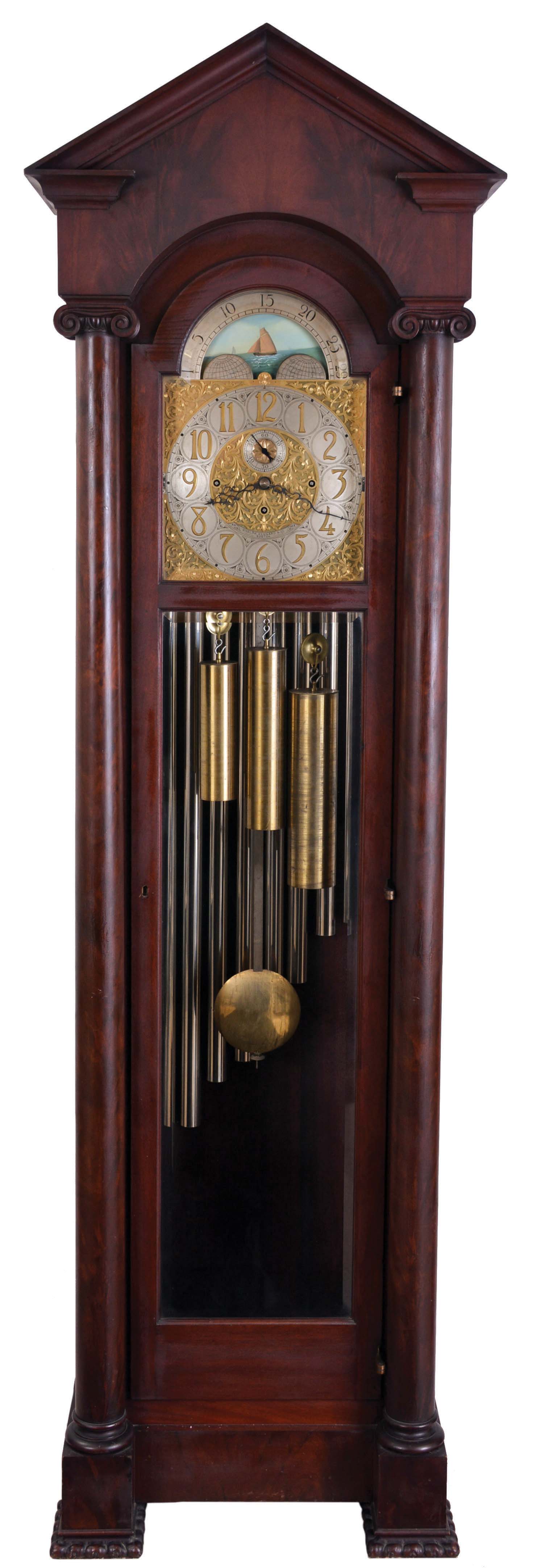 English, 3-train, 9-tube, brass dial tall clock, retailed by Bigelow, Kennard & Co., mahogany case with pediment top, door with two bevelled glasses, and with flanking columns having carved Ionic capitals, and resting on carved feet, composite dial with aplied numerals, silvered chapter ring and seconds bit, and displaying the phases of the moon, 8 day, quarter chiming, weight driven movemen — Antique Clocks Price Guide