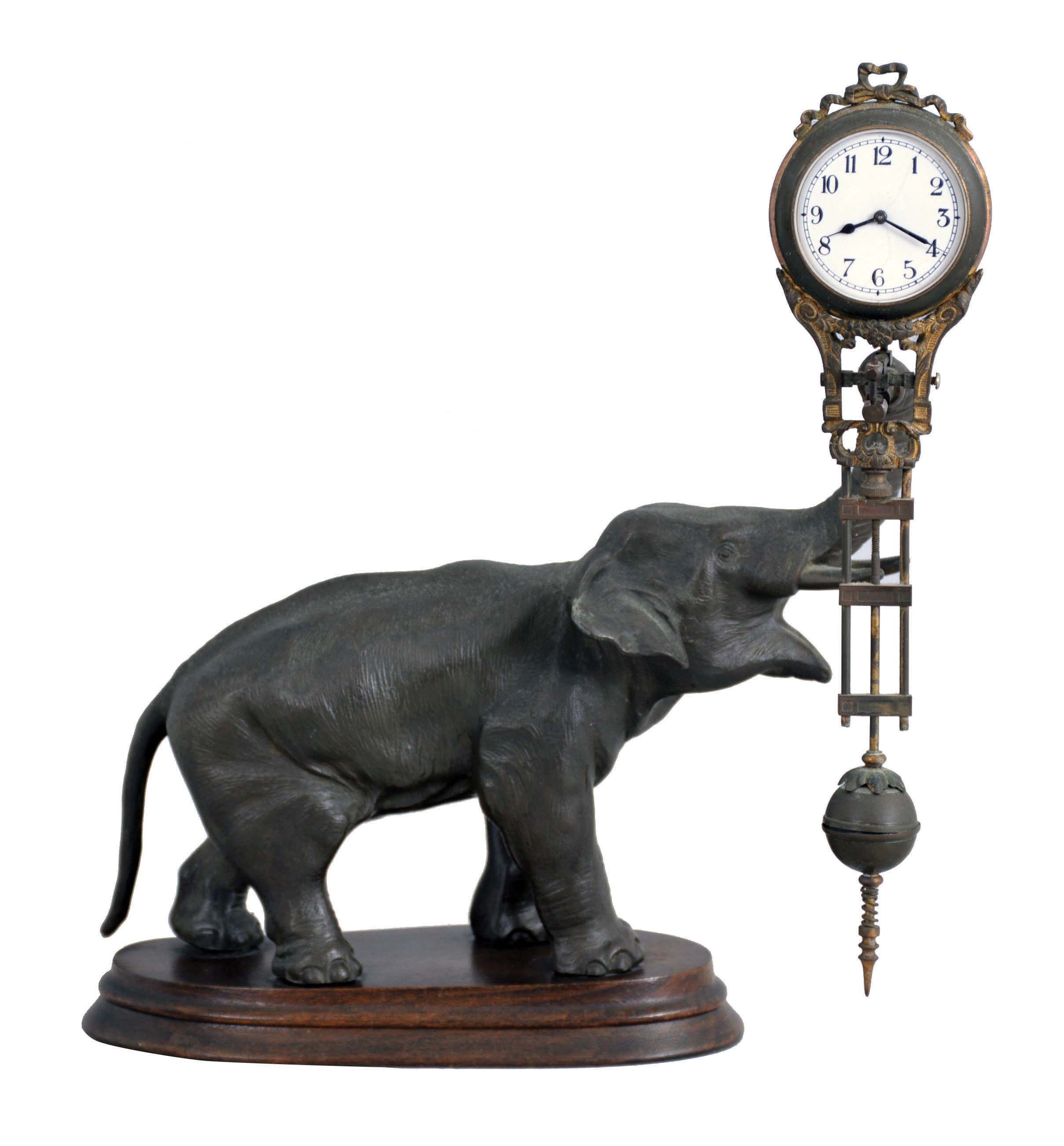 Junghans, Germany, "Elephant" model swinger, 8 day novelty timepiece, the patinated spelter elephant mounted to a molded beech base, his trunk supporting the compound pendulum with clock, Arabic numeral white enamel dial, blued steel hands, 8 day time only movement — Antique Clocks Price Guide