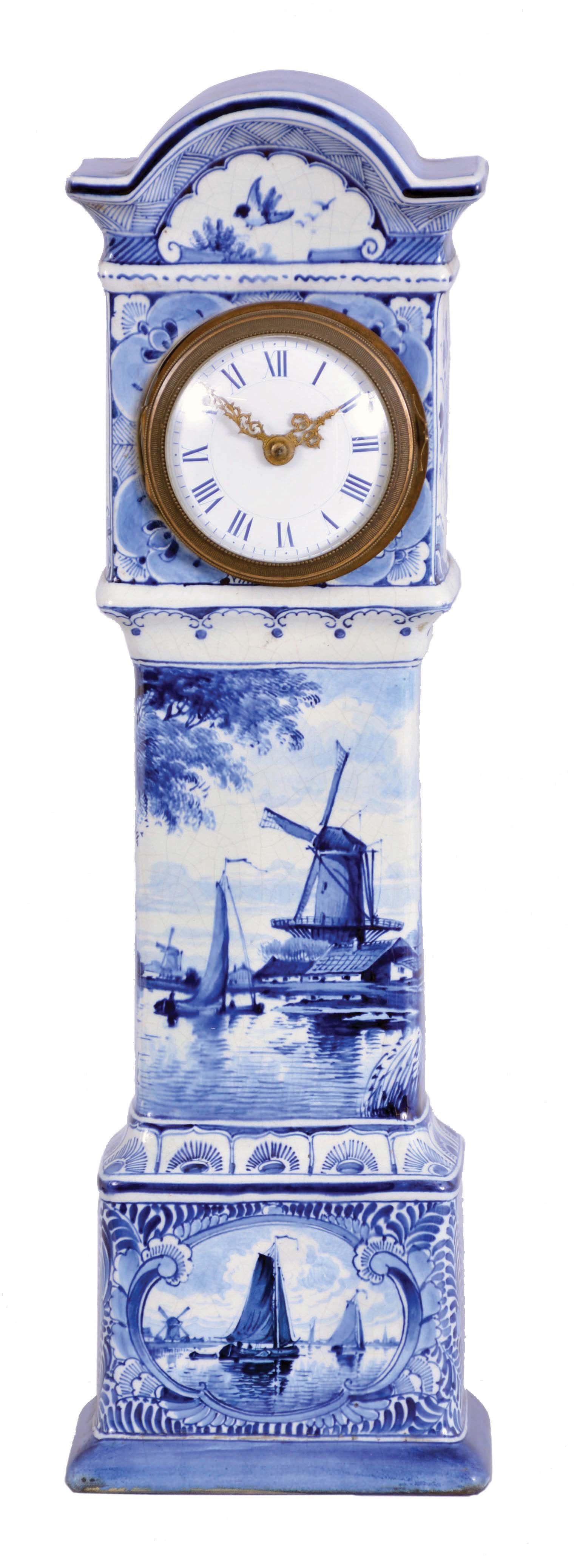 France, ceramic miniature tall clock, the earthenware case with blue, freehand decoration on a white ground, depicting harbor scenes with windmills on the trunk and base, with naturalistic ornament on the bonnet and base sides, Roman numeral white enamel dial with gilt Louis XV style hands, 8 day timepiece movement with cylinder platform, case bottom with makers mark — Antique Clocks Price Guide