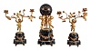 France, a three piece marble and gilt bronze mantel garniture, clock and candelabra on matching, variegated, green marble bases, the square plinths with incurved corners supporting attenuated columns draped with floral festoons, the larger, central base with three putti, holding aloft a patinated, spherical clock case with applied Roman numerals, and containing an 8 day, time and strike, pendule de Paris movement, the side pieces each with a single putto, with branching rose stem in each hand, the candle sockets of open rose form, clock dimensions listed