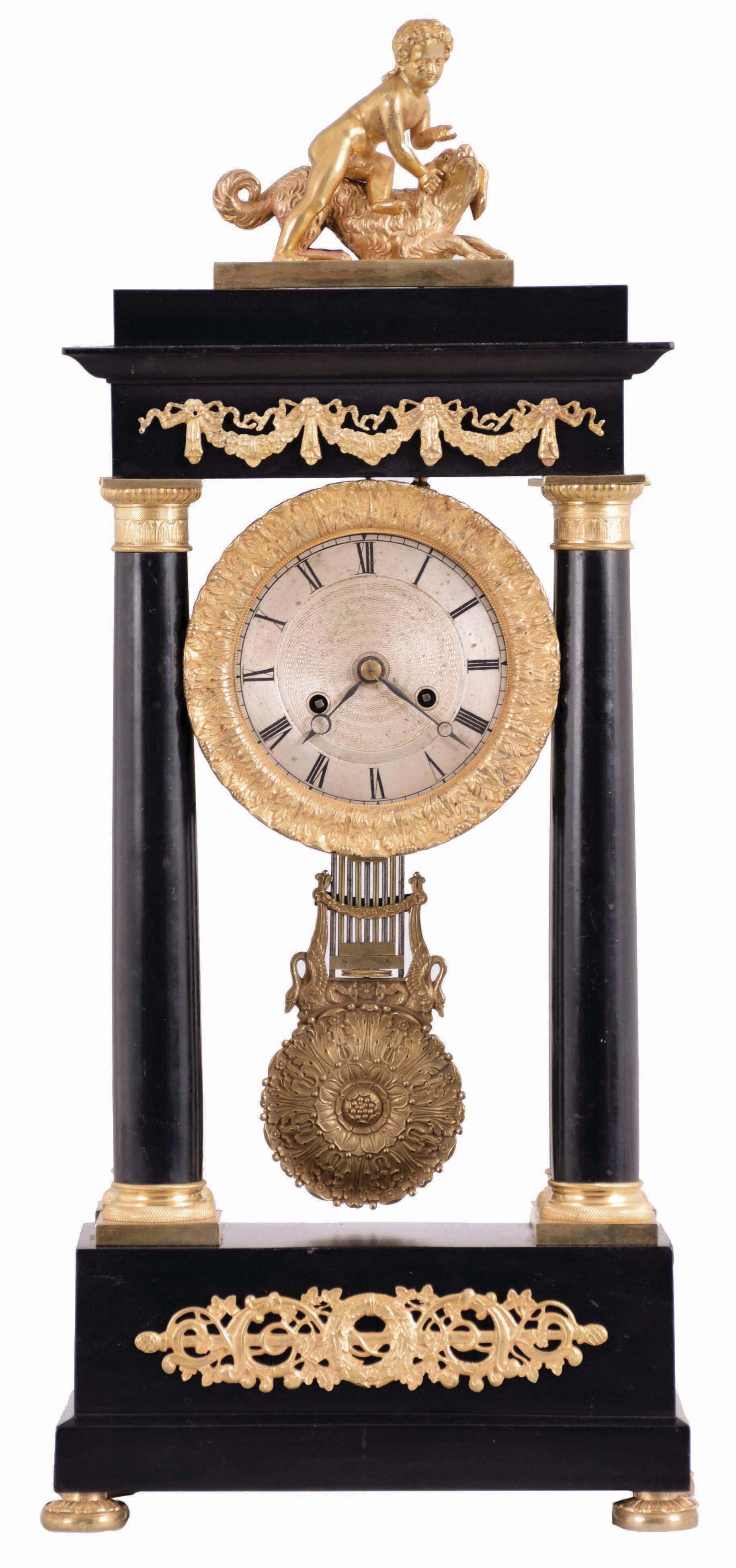 Delcamp, a Paris, portico clock, the ebonized case with classical, gilt mounts, the top with a figure of a boy and his dog, acanthus ornamented bezel with Roman numeral, engine turned silvered dial, blued steel Breguet style hands, 8 day, time and strike pendule de Paris movement, fancy gridiron pendulum with swans and foliate decoration — Antique Clocks Price Guide