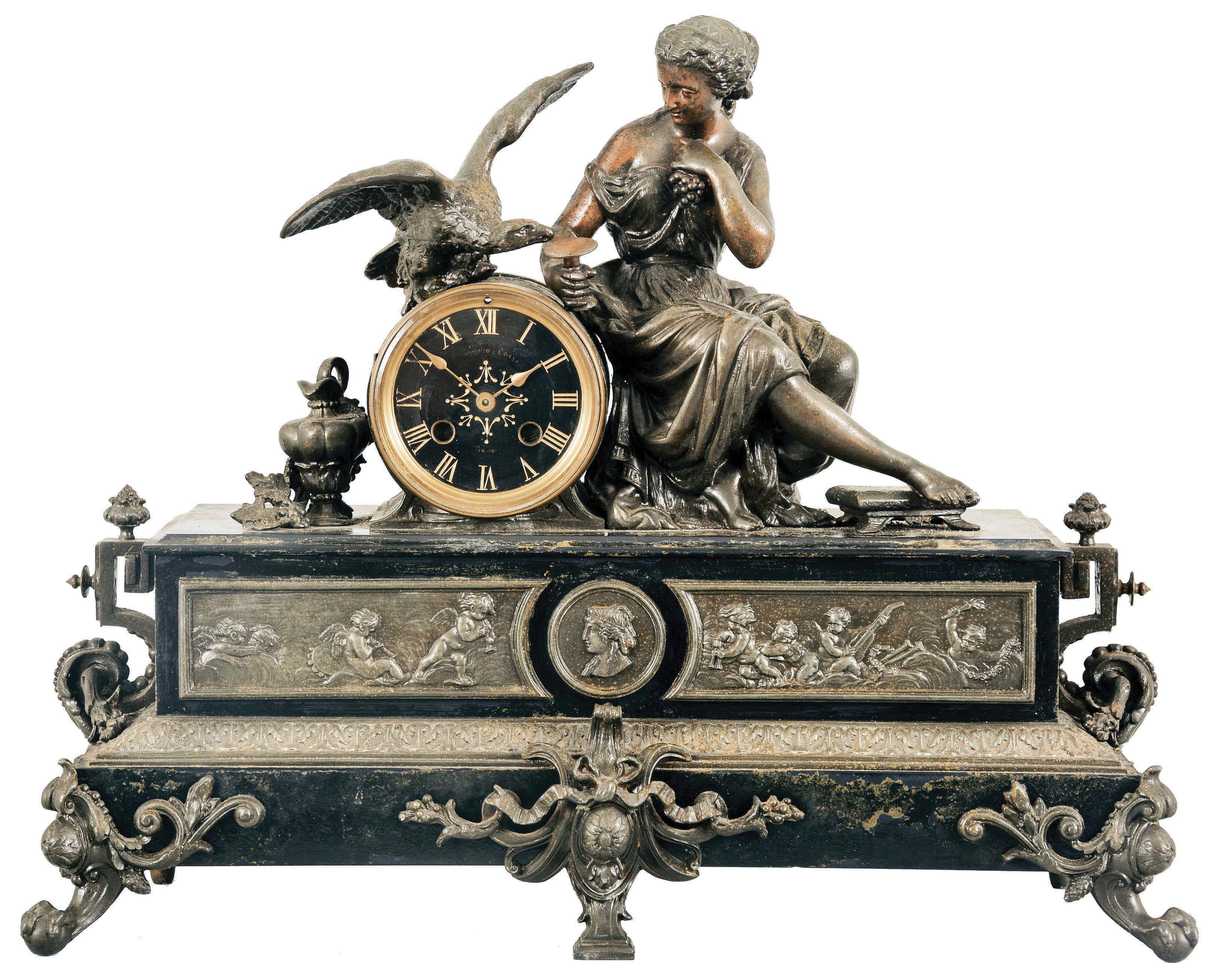 France, Figural Mantel Clock with Electric Movement, patinated Belgian slate case with brass and spelter figure and decoration, a seated young lady holding grapes and feeding a large raptor perched on top of the black and gold dial with roman numerals and gilt spade hands, the lower section of the case with classical puti facade centering on a goddess profile, all on feet of claw and ball feet and central bracket, the movement now with antiquated electric movement. — Antique Clocks Price Guide