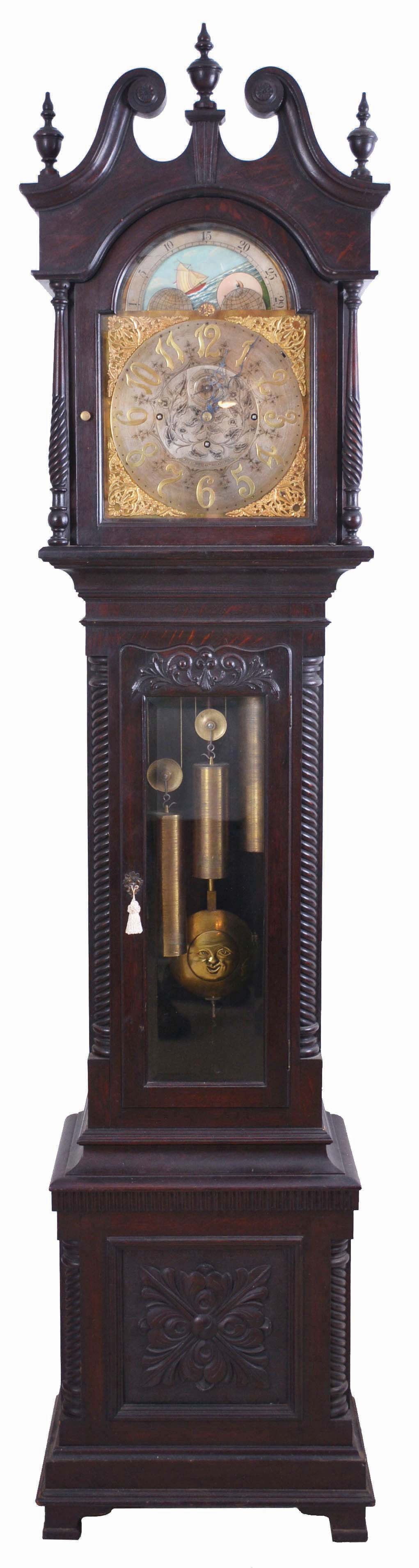 J.E. Caldwell, Philadelphia, (retailer) tall clock, 8 day, time, strike and chime on gong, three brass weight driven English movement with moon decorated pendulum in a Chippendale-style carved mahogany stained oak case with broken arch top and rope turned full columns flanking hood, three wooden finials, beveled glass on trunk door and rope turned quarter columns on trunk door and plinth. The brass dial has silvered chapter ring and center boss with engraving, chime silent selector, cast brass corner spandrels, moon phase and second's bit. — Antique Clocks Price Guide