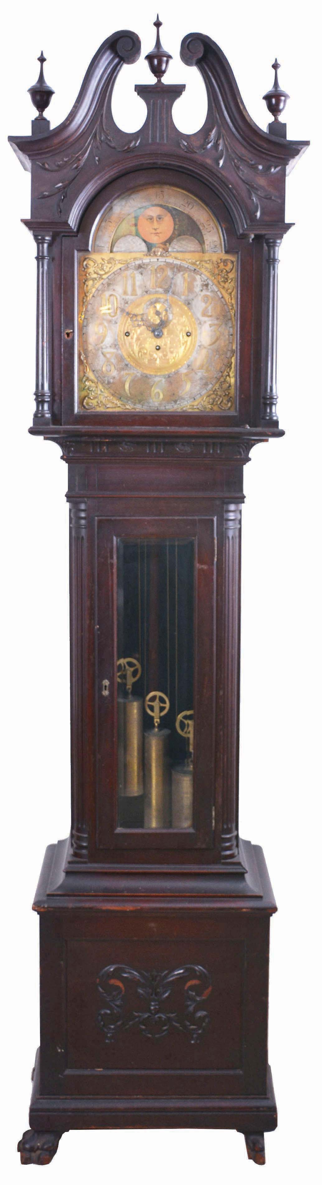 Germany, tall clock, 8 day, time, strike and chime on gongs, three brass weight driven movement in a mahogany case with beveled glass trunk door, broken arch top, paw feet, three wooden finials and applied moldings on base with brass dial, silvered chapter ring, applied brass spandrels, moon phase and seconds bit. — Antique Clocks Price Guide