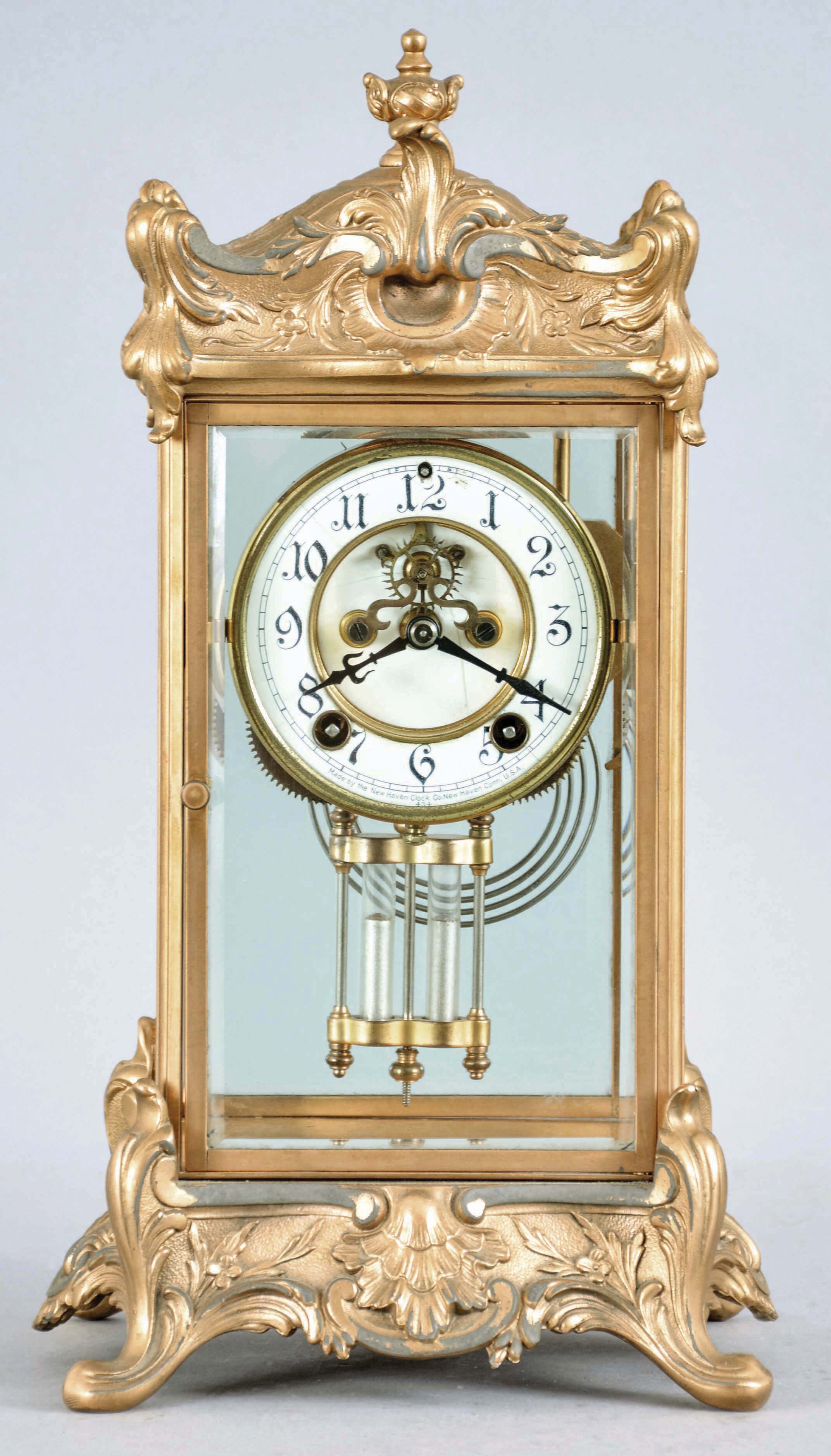 New Haven Clock Co., New Haven, Conn., "Thoreau" crystal regulator, 8 day, time and strike, spring driven movement in gilt metal case with four beveled glasses, porcelain dial with visible Brocot escapement. — Antique Clocks Price Guide