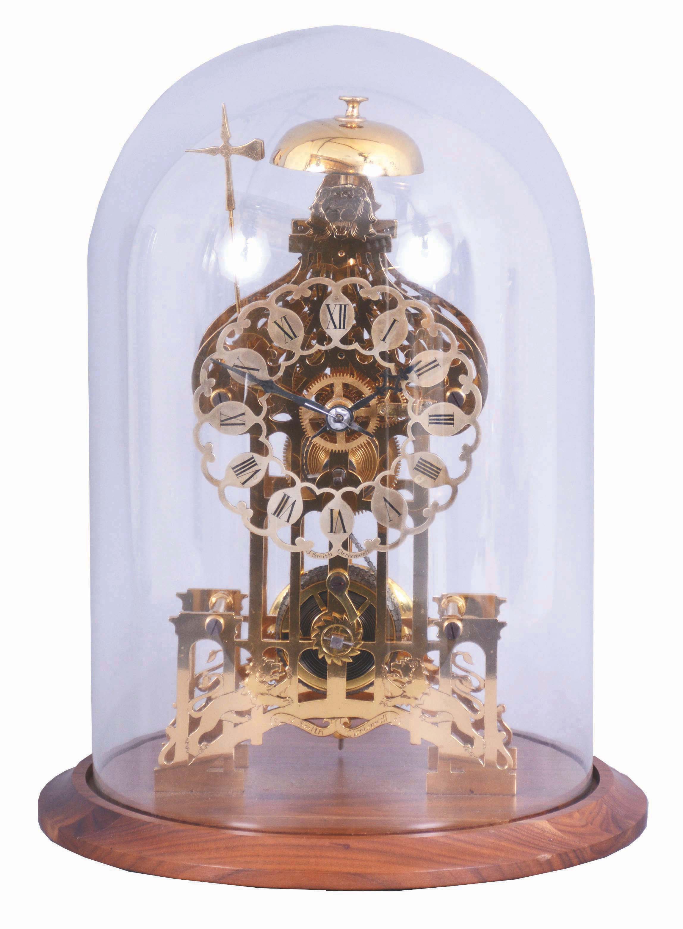 England, signed Smith, Clerkenwell, c1890 chain fusee pub movement, now in a modern skeletonized frame representing Brighton Pavilion, the frame appearing to have been cut on an EDM wire machine, and then polished by hand. The silvered dial is nicely fretted and the Roman Numerals are sharply engraved and black filled. The frame surmounted by a bell that is struck once on the passing of each hour. Covered by a round glass dome and mounted on a turned walnut base. — Antique Clocks Price Guide