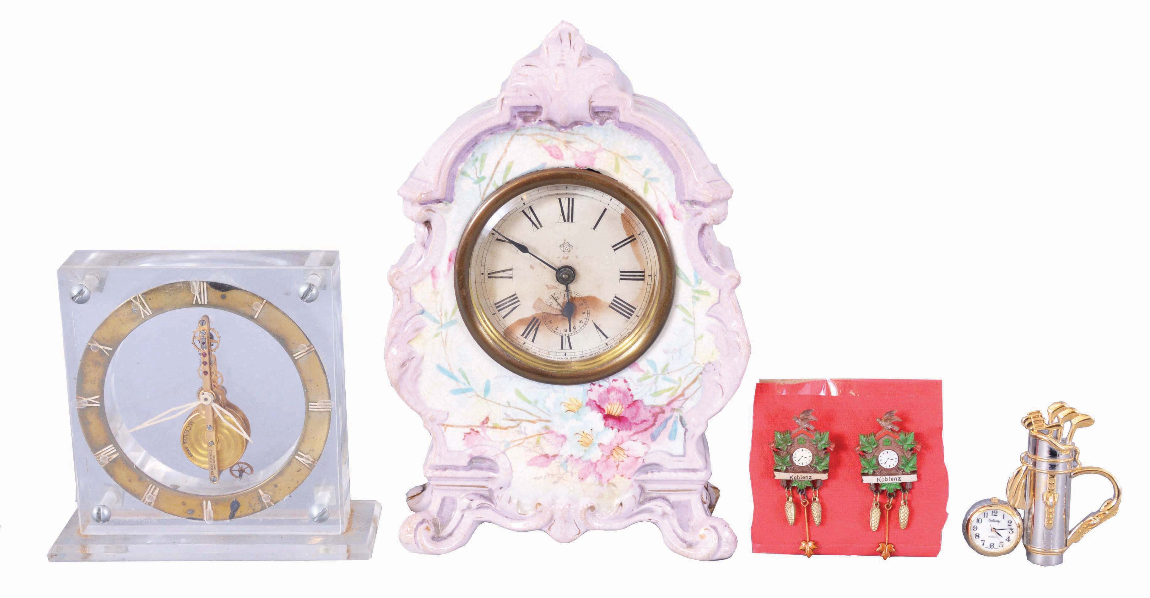 Clocks- 3 (Three): (1) Ansonia Clock Co., New York, miniature porcelain clock, 30 hour, time only in lavender outlined case with floral motif; (2) Switzerland, LeCoultre, desk clock with 16 jewel balance wheel movement in a clear acrylic case. (3) Boardman & Wells, Bristol, Conn., 30 hour, time and strike, weight wood movement half column & splat shelf clock. Lot also comes with a small desk clock in with a golf motif as well as two lapel pins in the shape of cuckoo clocks. — Antique Clocks Price Guide