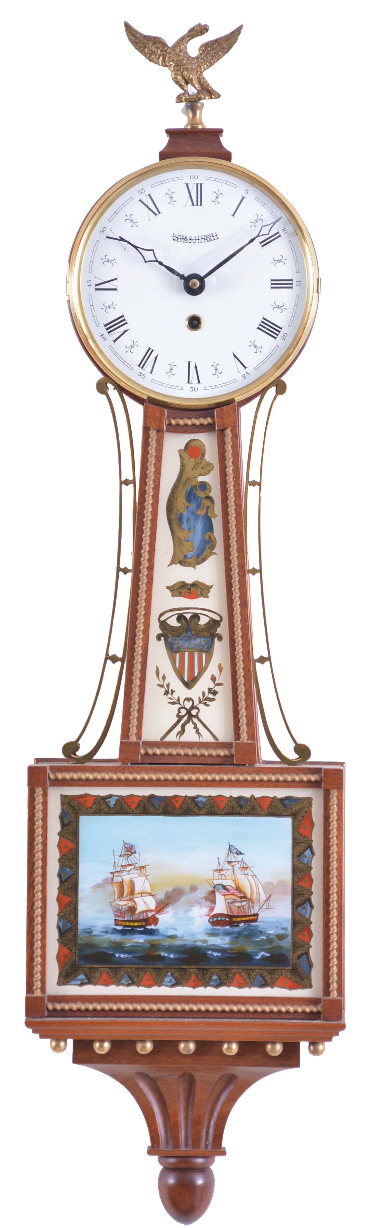 Elmer O. Stennes, Weymouth, Mass., Miniature Banjo Clock, roman numeral dial signed by maker, brass side ornaments flanking the waist glass with American shield, lower glass with British and American war ships in battle during the War of 1812 with a geometric border in red, blue and gold, both glasses held by rope molded mahogany frames, all resting on a carved mahogany pedestal eight day spring powered lever escapement movement and winding key. — Antique Clocks Price Guide