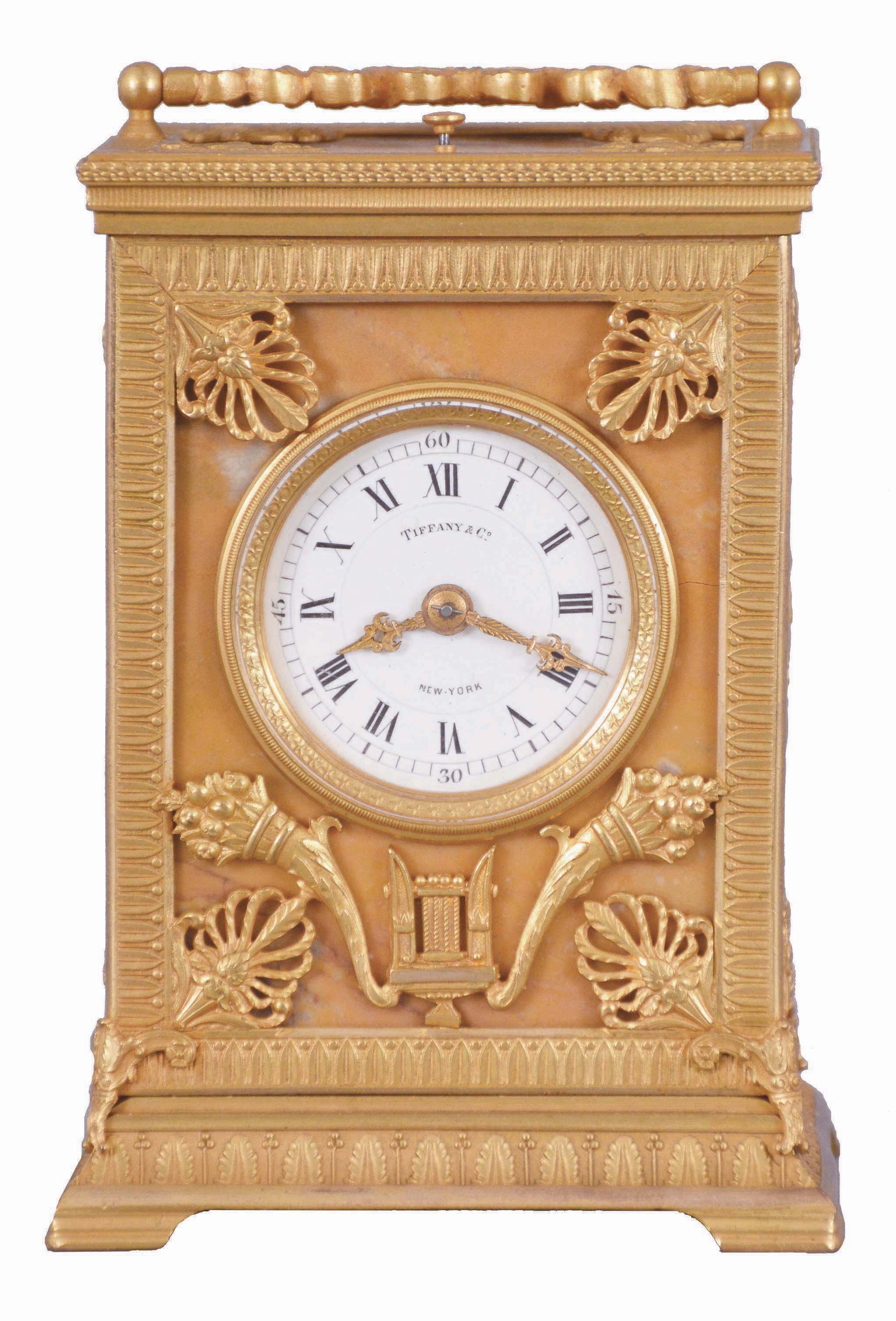 Ed. Chartier, Paris, for Tiffany & Co., New York, a fine gilt bronze and sienna marble carriage clock in the neoclassical style, the case set with five stone panels, within leaf molded surrounds having anthemion corners, the front with Roman numeral white enamel dial and gilt hands, above horn of plenty and lyre ornament, the case sides set with a single, dancing muse, and the top with carrying handle of bowknot and trailing ribbon form, with central laurel wreath, 8 day time, strike, and alarm movement with lever platform, repeating the last hour on demand, serial #12837, case and movement signed by Chartier — Antique Clocks Price Guide