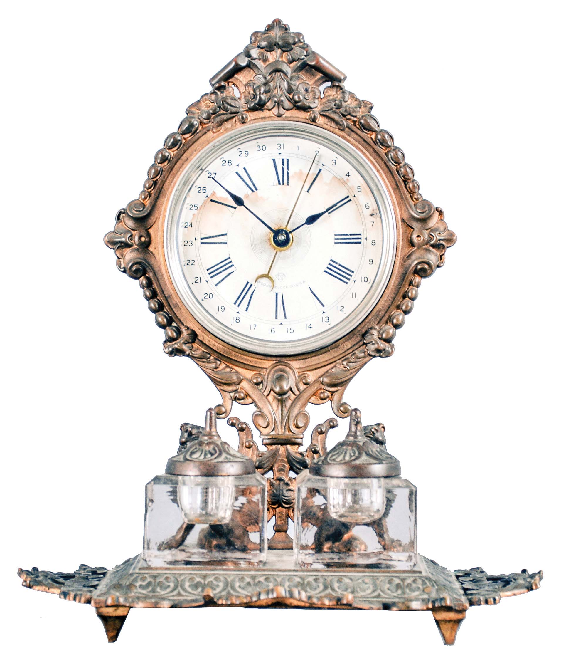 Ansonia Clock Co., New York, "Parlor Ink No. 3" inkstand clock, 30 hour, time and simple calendar, spring driven movement in a nickeled case with paper dial, cast brass base holding two glass inkwells with matching brass caps. — Antique Clocks Price Guide