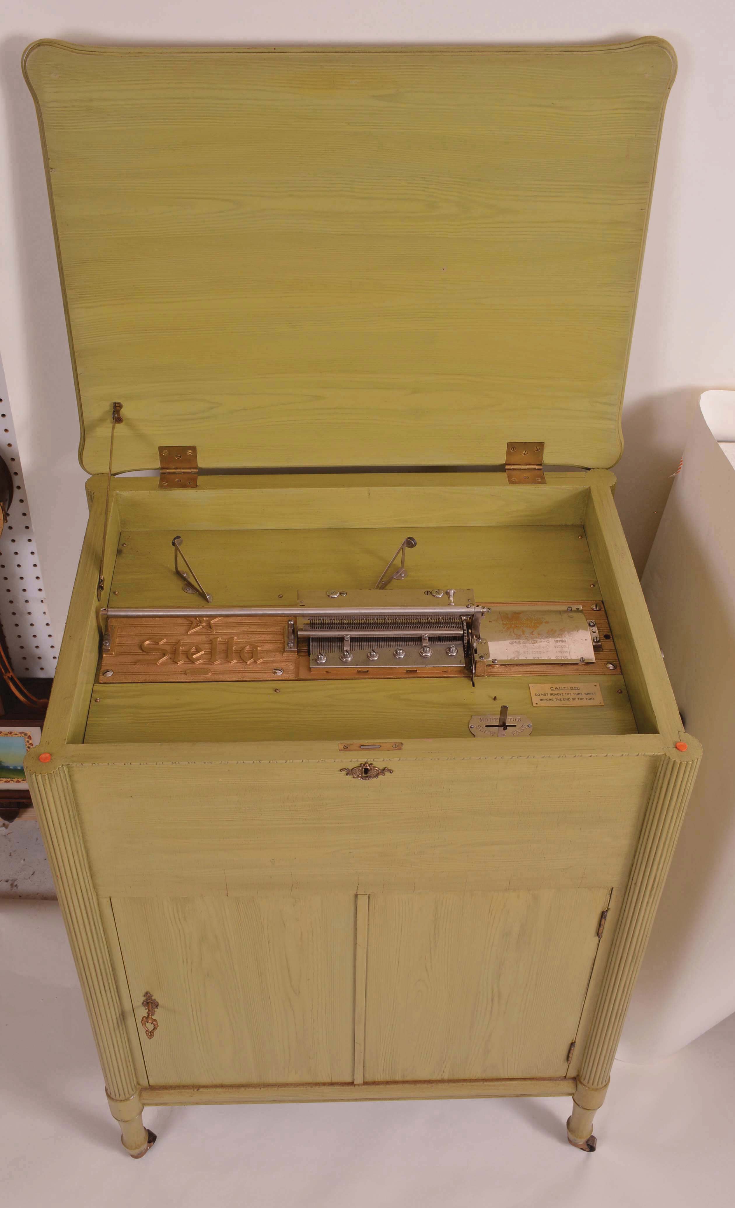 Music Box- Switzerland, "STELLA", 17 1/4 inch disc playing console music box,3 feet high, the cabinet painted appliance green in 1950, and with 40 discs, cabinet door opens and provides storage area for many discs. — Antique Clocks Price Guide