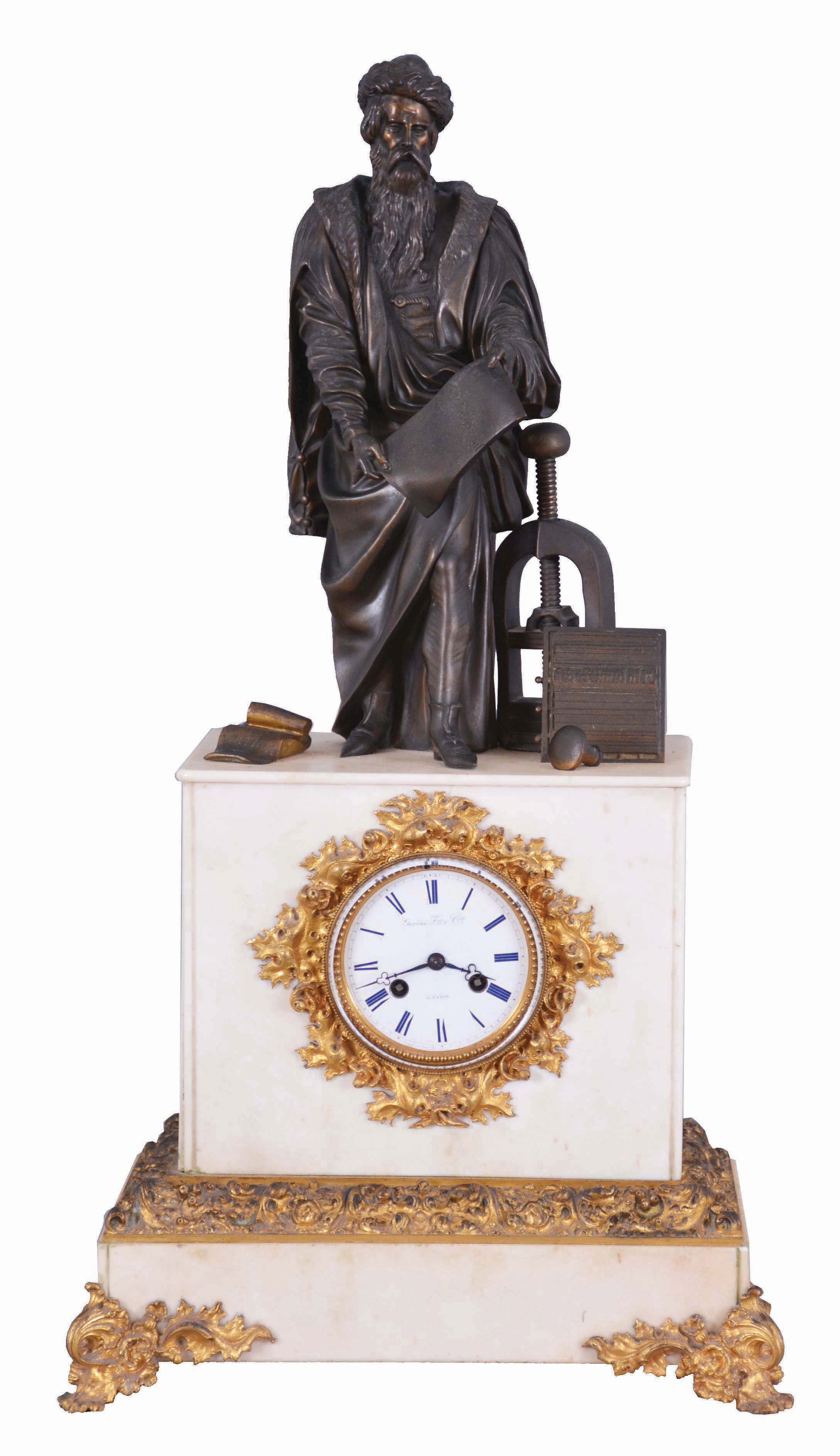 France, marble & bronze, monumental figure clock of Johann Gutenberg (1399--1468), standing next to his printing press, and a large chase with a line of type. He is holding a page just printed showing the reverse of the type in the chase. To the right of his foot is an open book, with the title 'BIBLIA LATINA', and beyond his left foot the ink tool or spreader. And with a well made bell strike movement, silk thread suspension. fancy gilt bezel and glazed dial cover. The porcelain dial signed Gorini Freres & Cie, a Paris. — Antique Clocks Price Guide