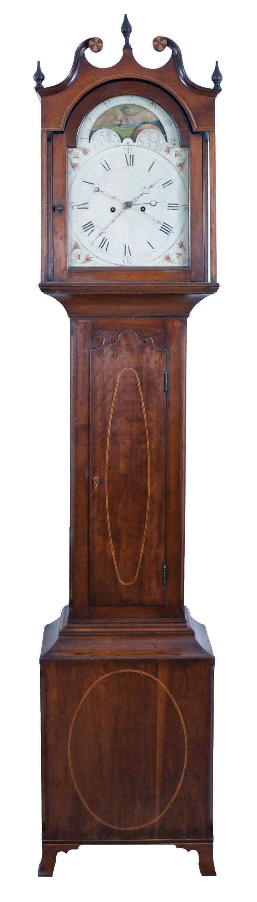 Pennsylvania tall clock, 8 days, time and bell strike, weight driven movement in a cherry case with oval inlay in plinth and on trunk door with stylized top, string inlay in quarter columns on trunk, square columns flanking hood and broken arch top with inlaid rosettes and three wooden finials on French feet. The painted metal dial has moon phase with ship and American flag, center sweep seconds and calendar on center arbor. — Antique Clocks Price Guide