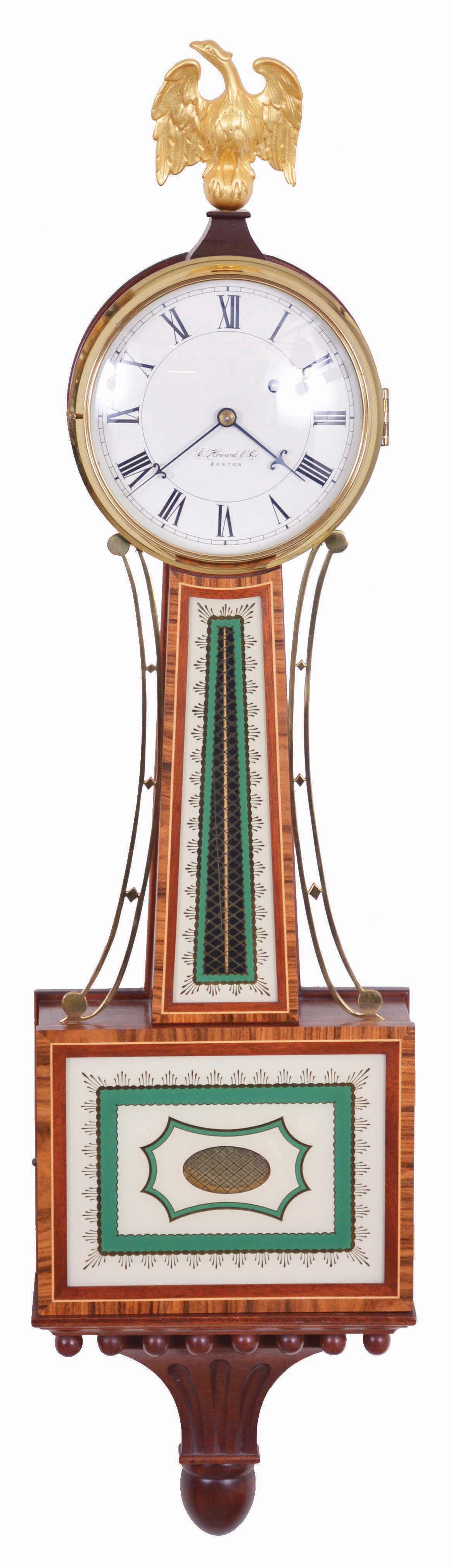 E. Howard & Co., Boston, Mass., "Model 95" Re-issue, Serial No. 124, gilt brass eagle surmounting the brass bezel which opens to the roman numeral dial marked "E. Howard & Co./Boston", cross banded inlaid frames house the reverse-painted glasses of the geometric and cross hatched pattern in green, gold leaf and off-white, cast brass side ornaments flank the waist section and a carved pedestal completes the design at the bottom, eight day brass time only movement stamped "E. Howard & Co./Boston/ 95" with recoil escapement, powered by a weight and regulated by a brass faced pendulum bob and brass rod. — Antique Clocks Price Guide