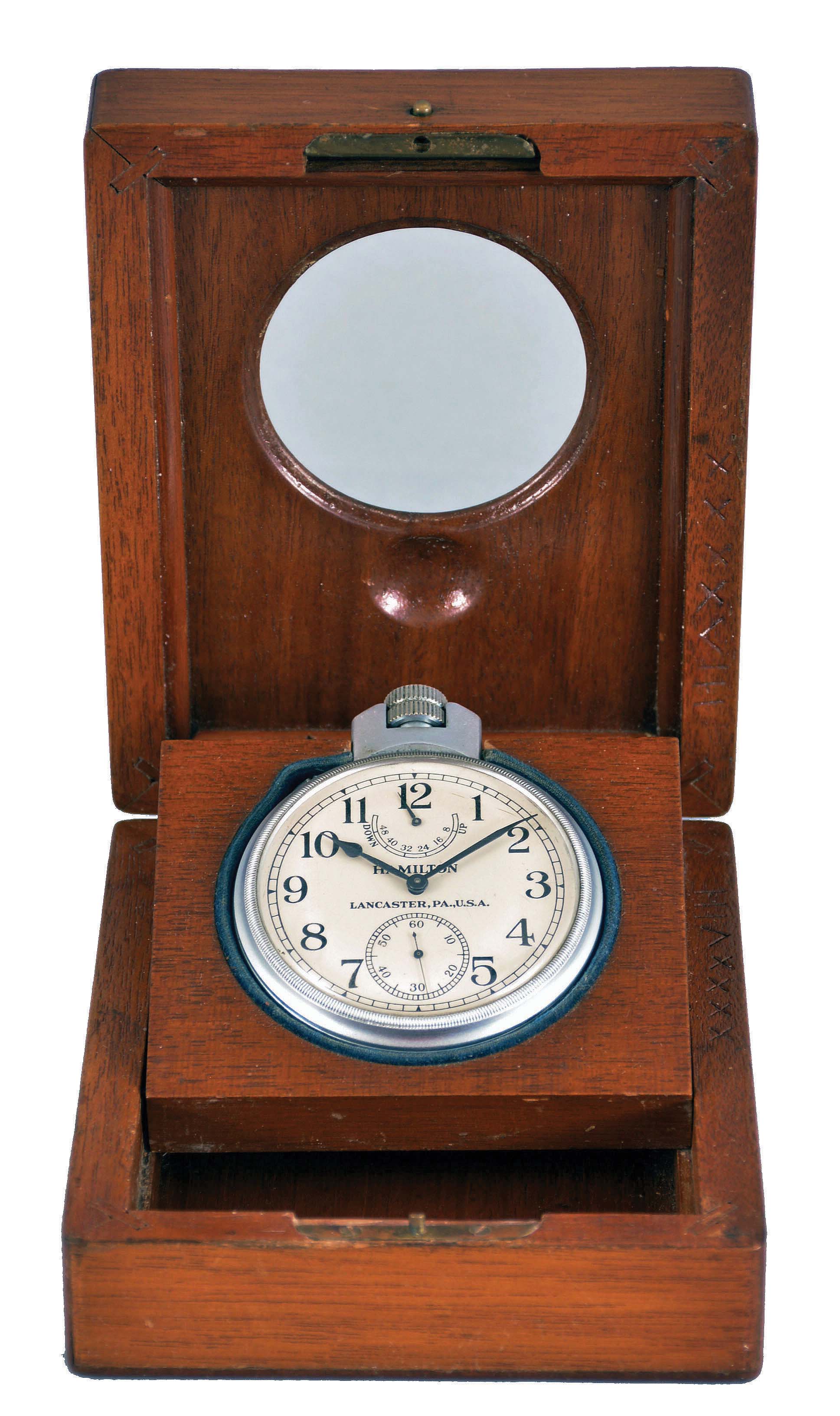 Hamilton Watch Co., Lancaster, Penn., model 22 chronometer watch with wind indicator, 35 size, 21 jewels, stem wind, pin set, adjusted to 6 positions and temperature, straight line damascened nickel plate movement, with lever escapement and micrometric regulator, Arabic numeral silvered metal dial, black steel spade and poker hands, serial #2F12833, the timepiece contained in a mahogany box with viewing aperture, c1940 — Antique Clocks Price Guide