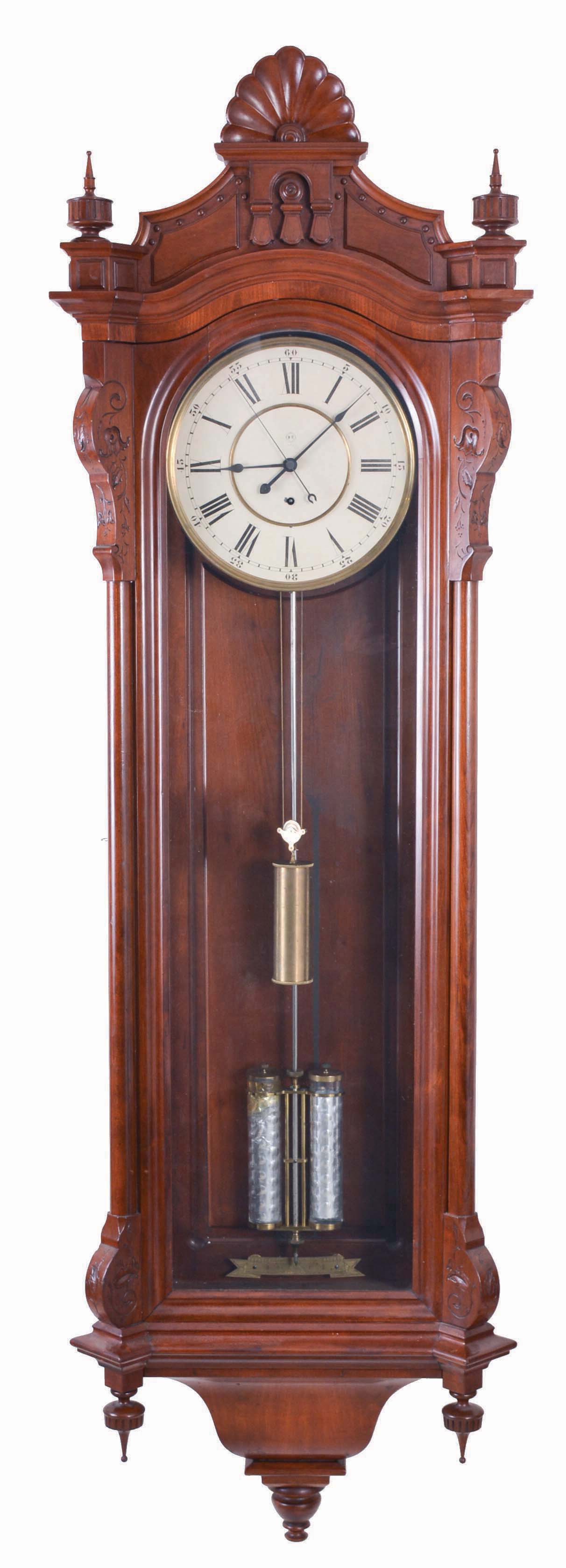 Seth Thomas Clock Co., Thomaston, Conn., "Regulator No. 19", jewelers hanging regulator, 8 day, time only weight driven movement, having a mercury compensated pendulum with two thumbprint jars, and contained in a cherry case with carved, turned, and molded ornament, with Roman numeral painted metal dial, steel spade hands, and center sweep seconds — Antique Clocks Price Guide