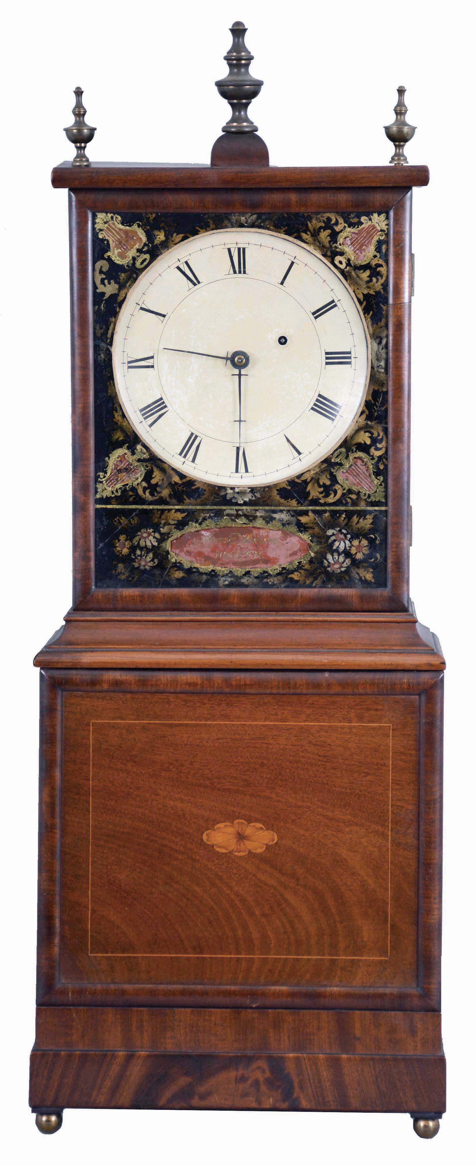 Aaron Willard, Boston, Massachusetts, dish dial mahogany shelf clock, reverse-painted glass with shields, stenciled flowers and lower cartouche inscribed "Aaron Willard/Boston" all over the iron roman numeral dish dial, the lower veneered wooden panel with line and central marquetry inlay resting on the flat veneered base and brass ball feet, eight day time only brass movement with pendulum and lead weight. — Antique Clocks Price Guide