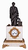 France, marble & bronze, monumental figure clock of Johann Gutenberg (1399--1468), standing next to his printing press, and a large chase with a line of type. He is holding a page just printed showing the reverse of the type in the chase. To the right of his foot is an open book, with the title 'BIBLIA LATINA', and beyond his left foot the ink tool or spreader. And with a well made bell strike movement, silk thread suspension. fancy gilt bezel and glazed dial cover. The porcelain dial signed Gorini Freres & Cie, a Paris.