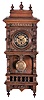 Germany, a miniature "Freischwinger", the walnut case with deeply molded top, recessed frieze with applied brass ornament, the door also with applied, split turnings and brass ornament, and open well with balustrade and supporting brackets, Roman numeral brass dial with engraved center, blued steel hands, 8 day timepiece movement with deadbeat escapement, and brass pendulum, with ornament matching the dial