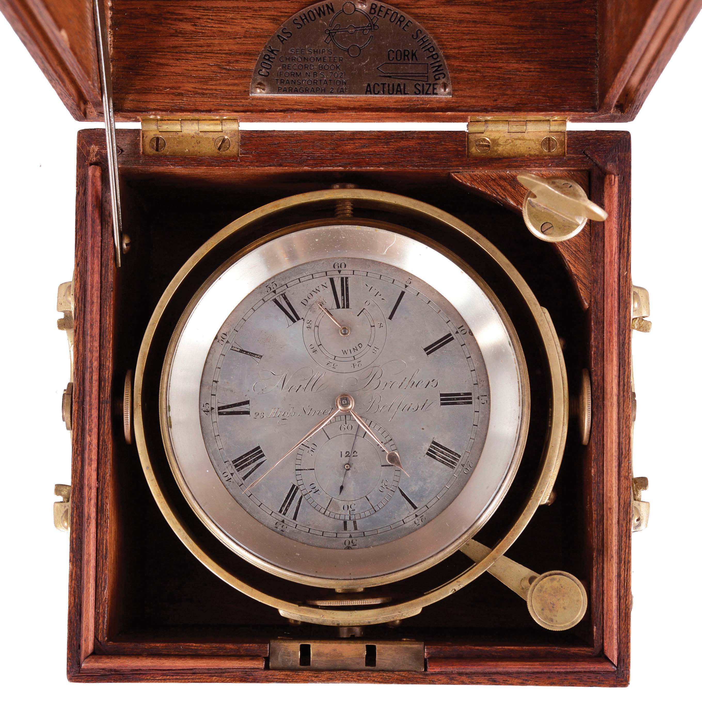 Neill Brothers, Belfast, two day marine chronometer, 10 jewel fusee movement with spotted plates, Earnshaw's escapement, freesprung, cut bimetallic balance, diamond endstone, and blued steel helical balance spring, Roman numeral silvered dial with wind indicator and gold spade and poker hands, with gimballed brass bowl, and contained in a three tier mahogany box with brass handles, serial #122 — Antique Clocks Price Guide