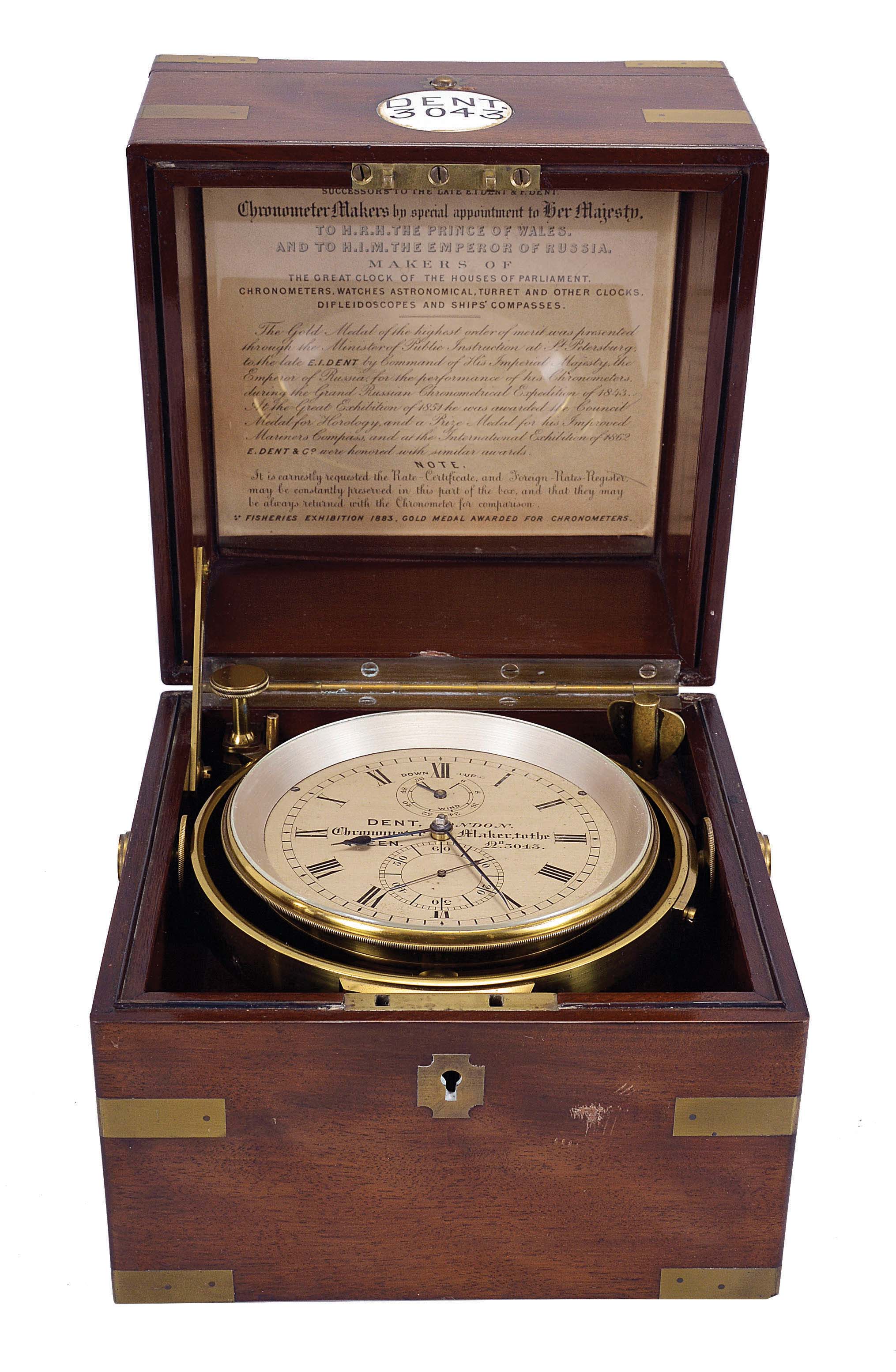 Dent, London, a good two day marine chronometer with Dent's staple balance, 11 jewel, spotted fusee movement with Earnshaw's escapement, freesprung bimetallic staple balance with blued helical balance spring and diamond endstone, Roman numeral silvered dial with wind indicator, blued steel spade and poker hands, with lacquered brass bowl and gimbals, and contained in a three tier mahogany and mahogany veneer box with brass furniture, the front with round plaque marked "Dent 3043", the inside of the lid with E. dent & Co. label — Antique Clocks Price Guide