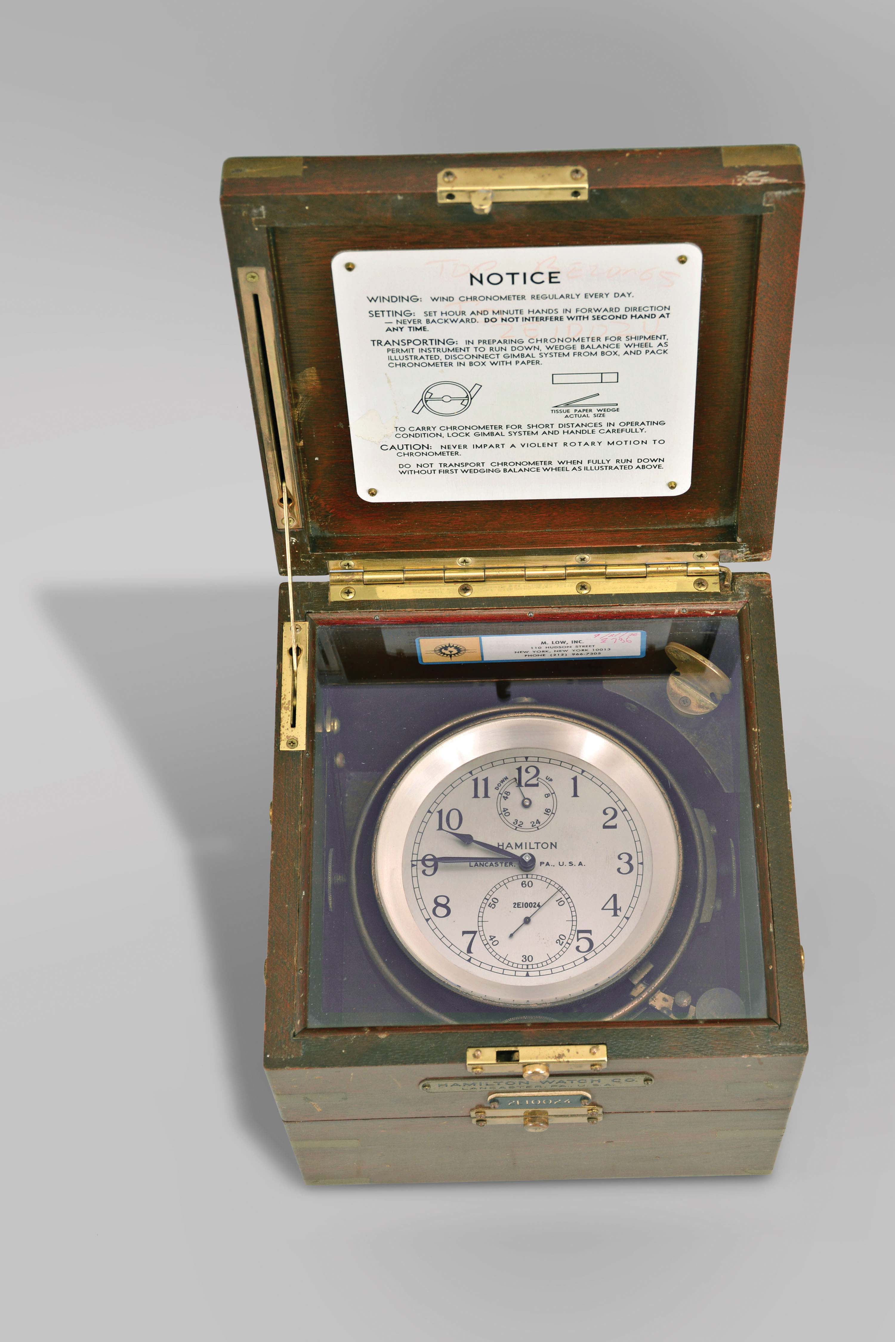 Hamilton Watch Co., Lancaster, Penn., model 21 marine Chronometer, 14 jewel, key wind and set fusee movement with straight line damascened nickel plates, spring detent escapement, large monometallic balance and helical balance spring, Arabic numeral metal dial with wind indicator, black painted steel spade and poker hands, with gimbaled brass bowl, contained in a three tier mahogany box with brass furniture, serial #2E10024 — Antique Clocks Price Guide