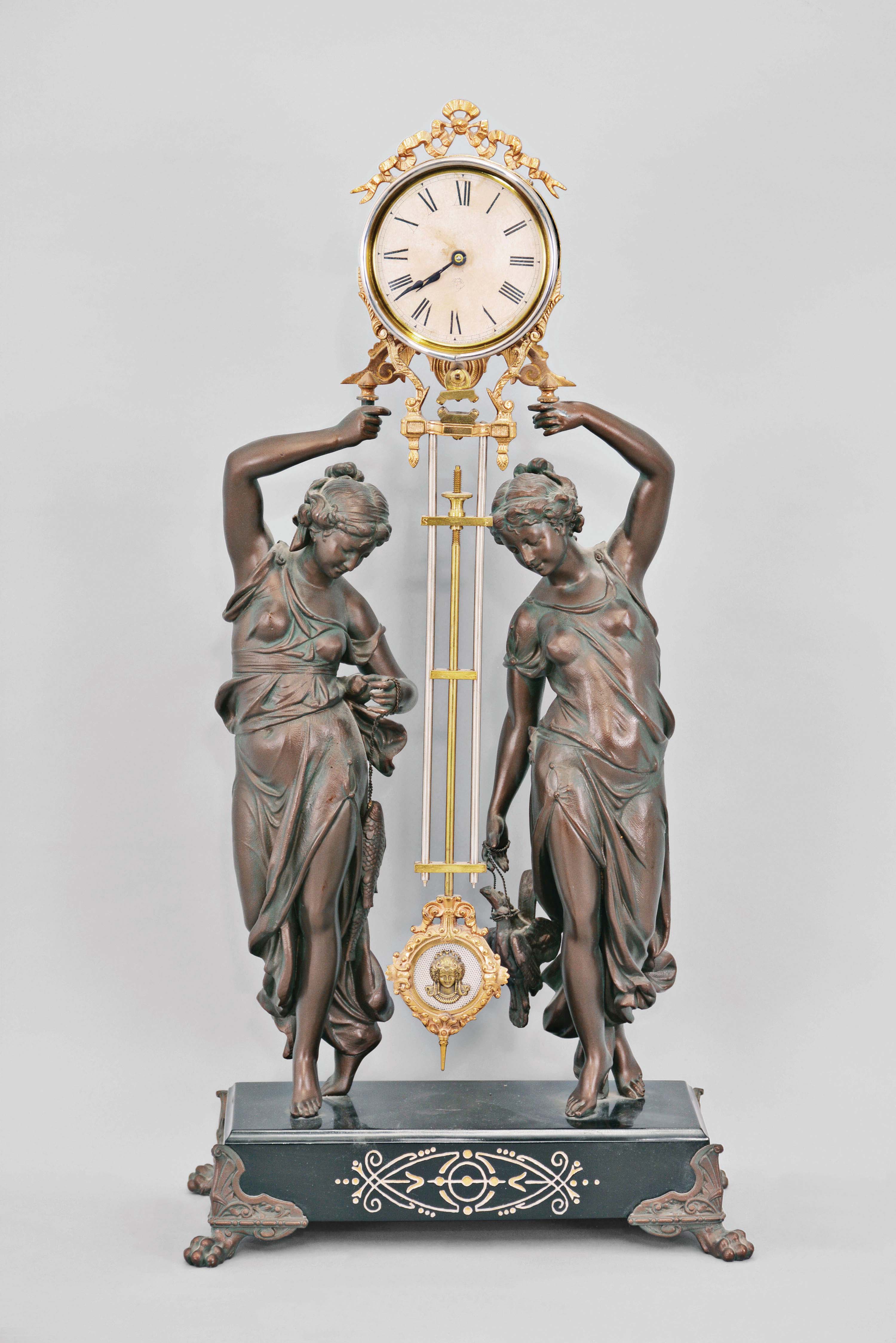 Ansonia Clock Co., New York, "Double Figure Swing" clock with a spring driven, 8 day, timepiece movement in a gilt and nickel cannister-style case with a bronze finished spelter statue on an enameled iron base. — Antique Clocks Price Guide