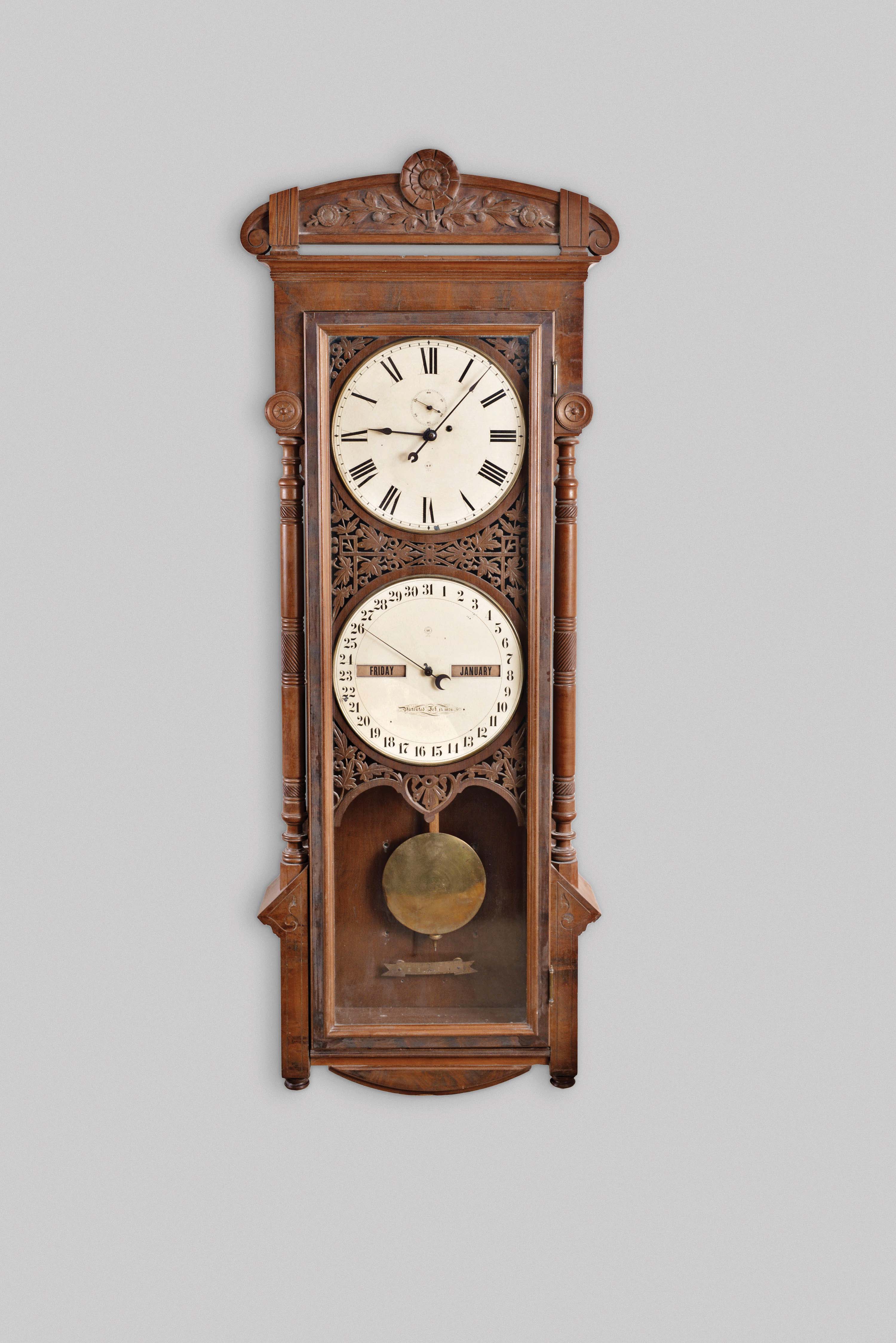 Seth Thomas Clock Co., Thomaston, Conn., "Office Calendar No. 11" hanging jeweler's regulator, 8 day, weight driven movement with perpetual calendar, in a walnut case with carved crest and carved and pierced dial surround and painted metal dials — Antique Clocks Price Guide