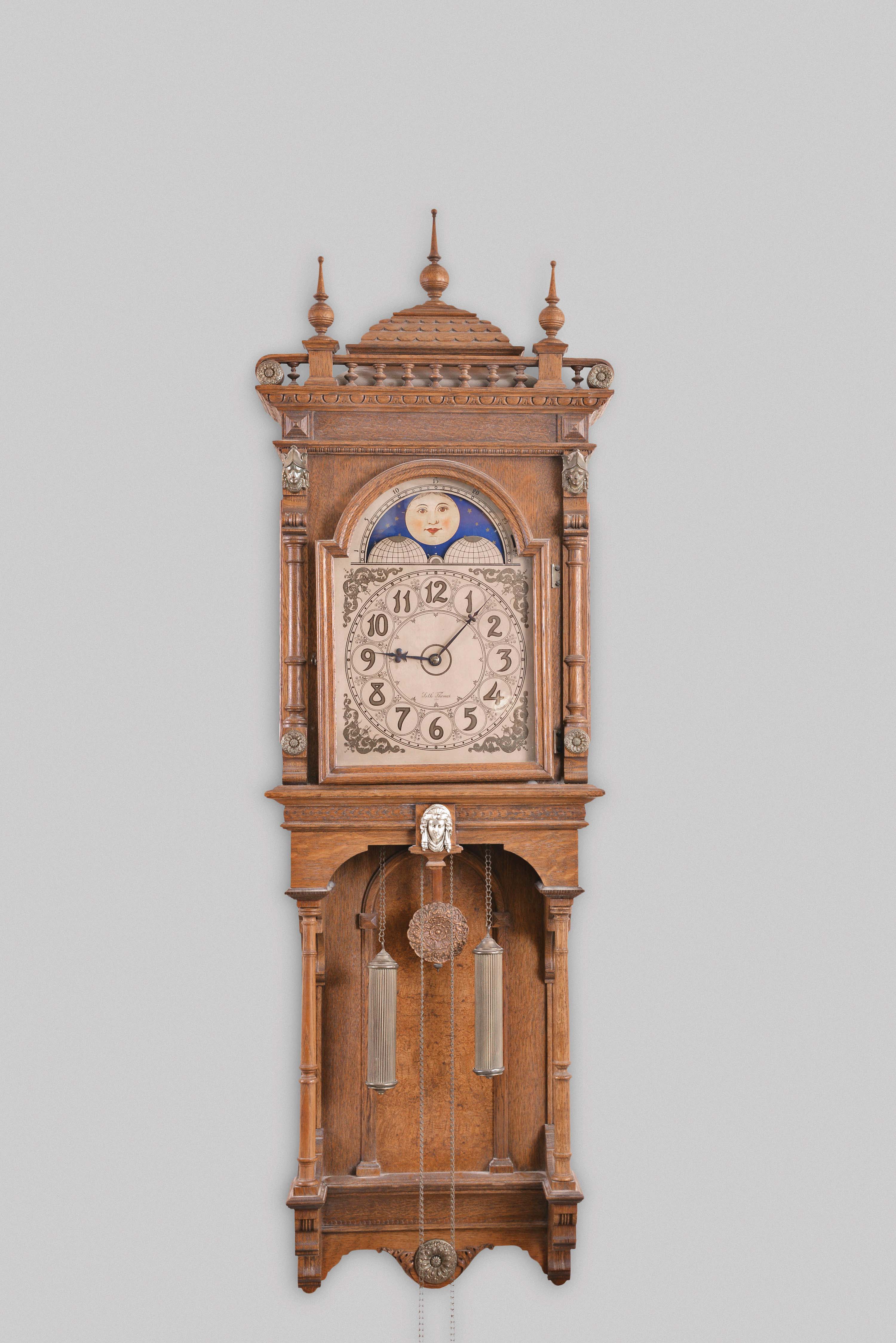 Seth Thomas Clock Co., Thomaston, Conn., "Jupiter" hanging, 8 day, time and bell strike weight driven movement in an open well oak case with three Jenny Lind busts and pressed brass ornaments, silvered metal dial with moon phase — Antique Clocks Price Guide