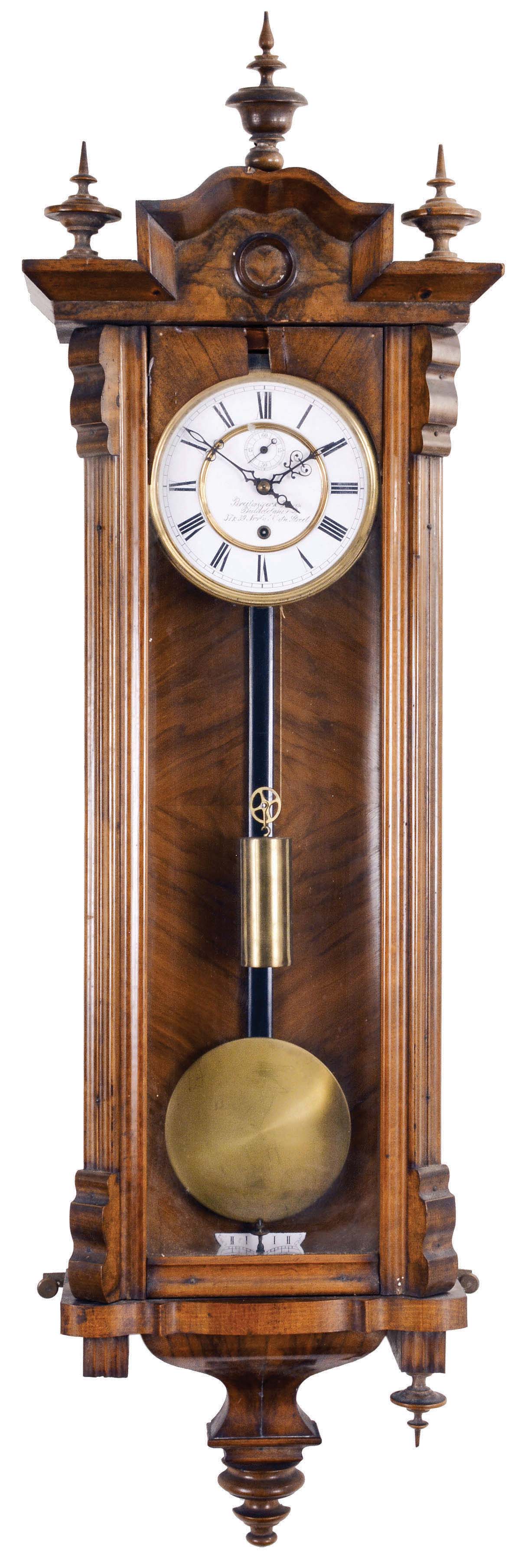Gustav Becker, Freiberg, Germany, Vienna style regulator, 8 day, time only, weight driven movement in a walnut case with fluted columns flanking the door glass and turned ornaments, brass clad pendulum, white enamel dial reading in part "Breitinger & Kunz / Philadelphia", subsidiary seconds, and blued steel hands. — Antique Clocks Price Guide