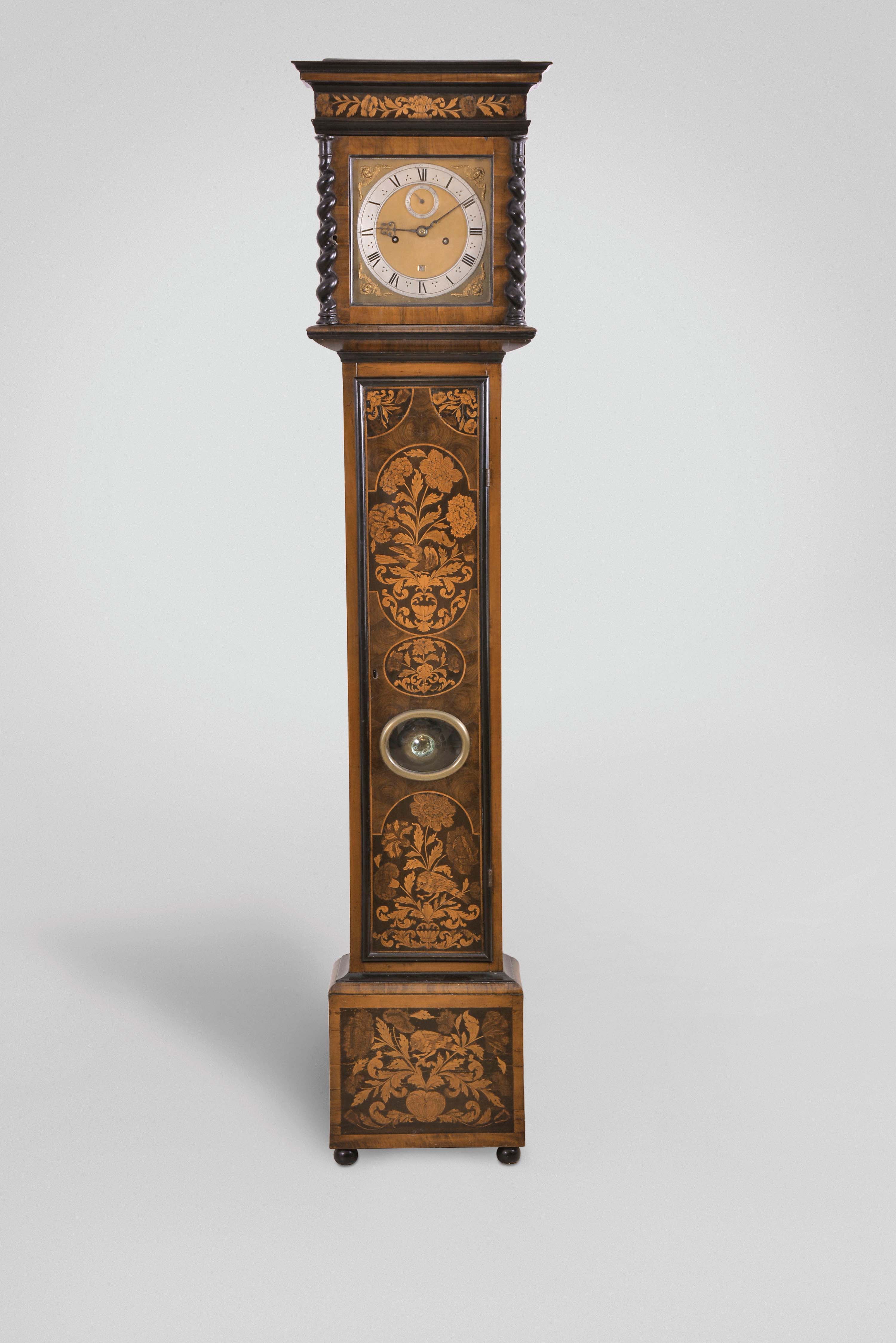 Joseph Knibb, London, a late 17th century, two train tall clock with associated case, the 8 day, six pillar time and strike movement with riveted latches, bolt and shutter maintaining power, count wheel striking, and recoil escapement, 9 1/2" square brass dial with matted center, roman numeral silvered chapter ring, date aperture above 6:00, cherub spandrels, and signed "Joseph Knibb Londini Fecit", finely finished, fretted, blued steel hands, the oak case in the manner of Jasper Braem, with ebonized moldings and ball feet, oyster veneers, marquetry panels with gadrooned urns issuing flowers and foliage, and with perching birds, flat top bonnet with ebonized Solomonic columns, glazed sides, and marquetry frieze, with brass clad pendulum, brass cased weights, brass pulleys, and correct winding key — Antique Clocks Price Guide