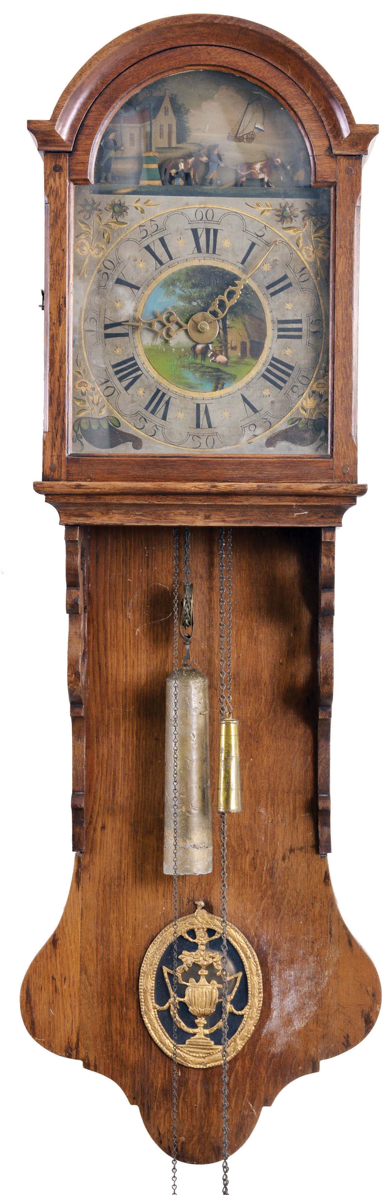 Holland, Friesland Staartklok 30 hour, time and strike, weight driven movement with alarm and endless chain driving animated farm scene in the arch driven off a pulley on the front of the escape wheel arbor, in an oak case with arch top bonnet, the pendulum aperture with stamped pewter ornament. The arcaded Roman numeral painted dial has polychrome floral corner spandrels, vignette of barn scene in center and cast brass hands, tapered weight — Antique Clocks Price Guide